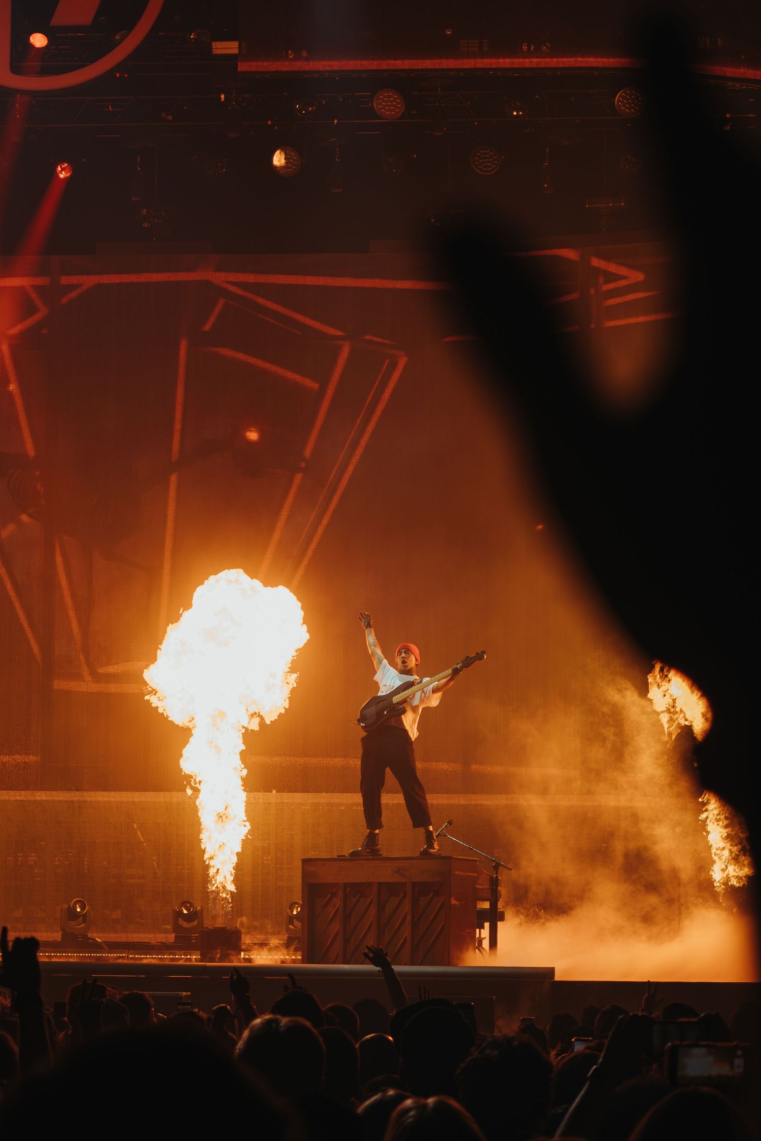 Performer on stage with dramatic pyrotechnic fire effects in dark venue.