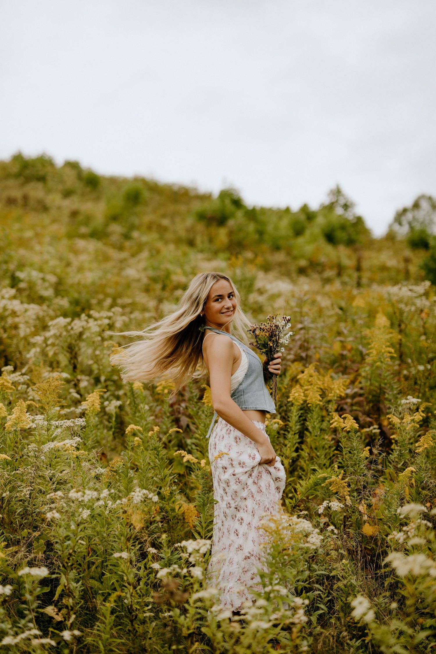 Whimsical portrait with flowing floral dress in meadow of late summer wildflowers.