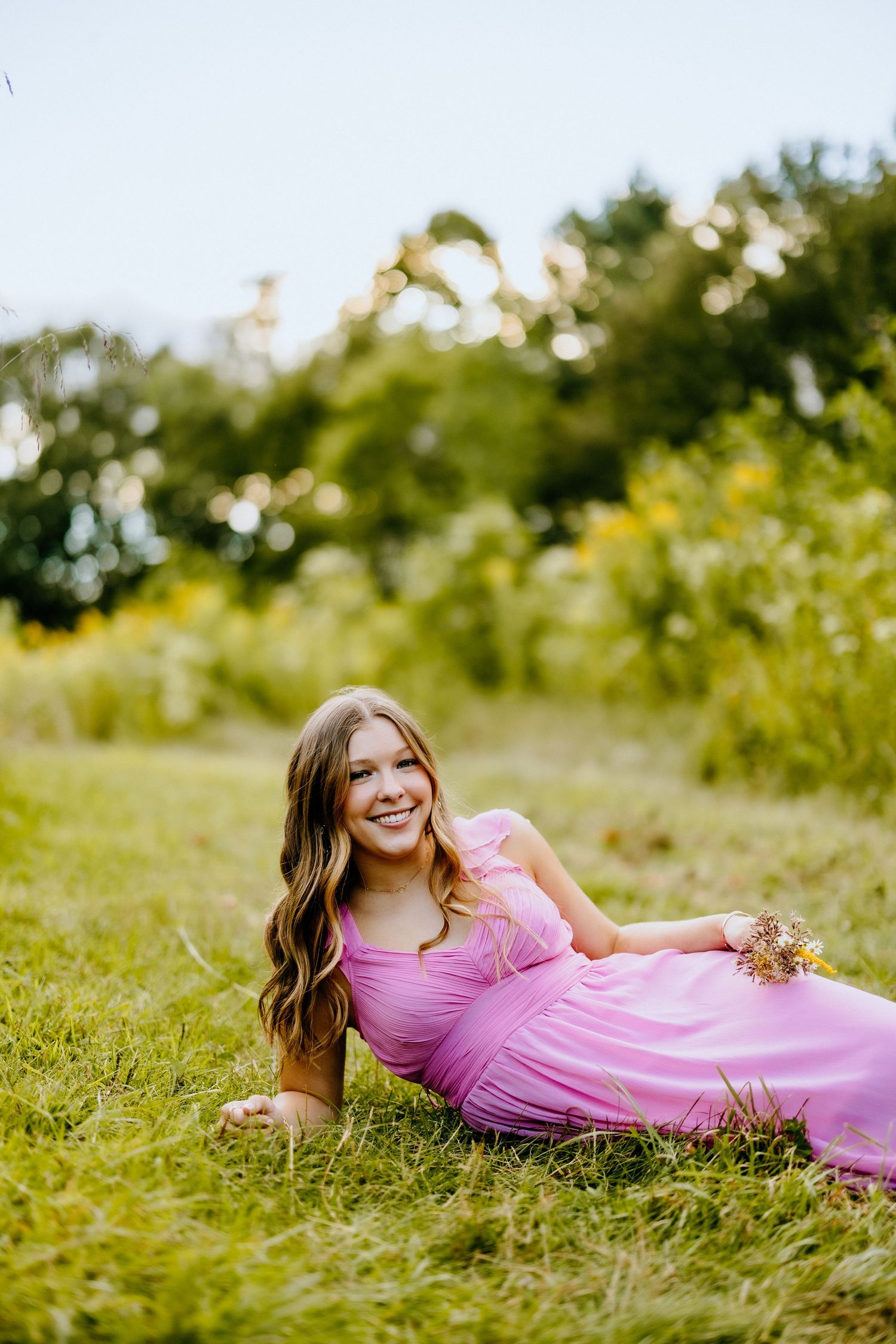 A pink dress spreads gracefully across green summer grass in warm afternoon light.