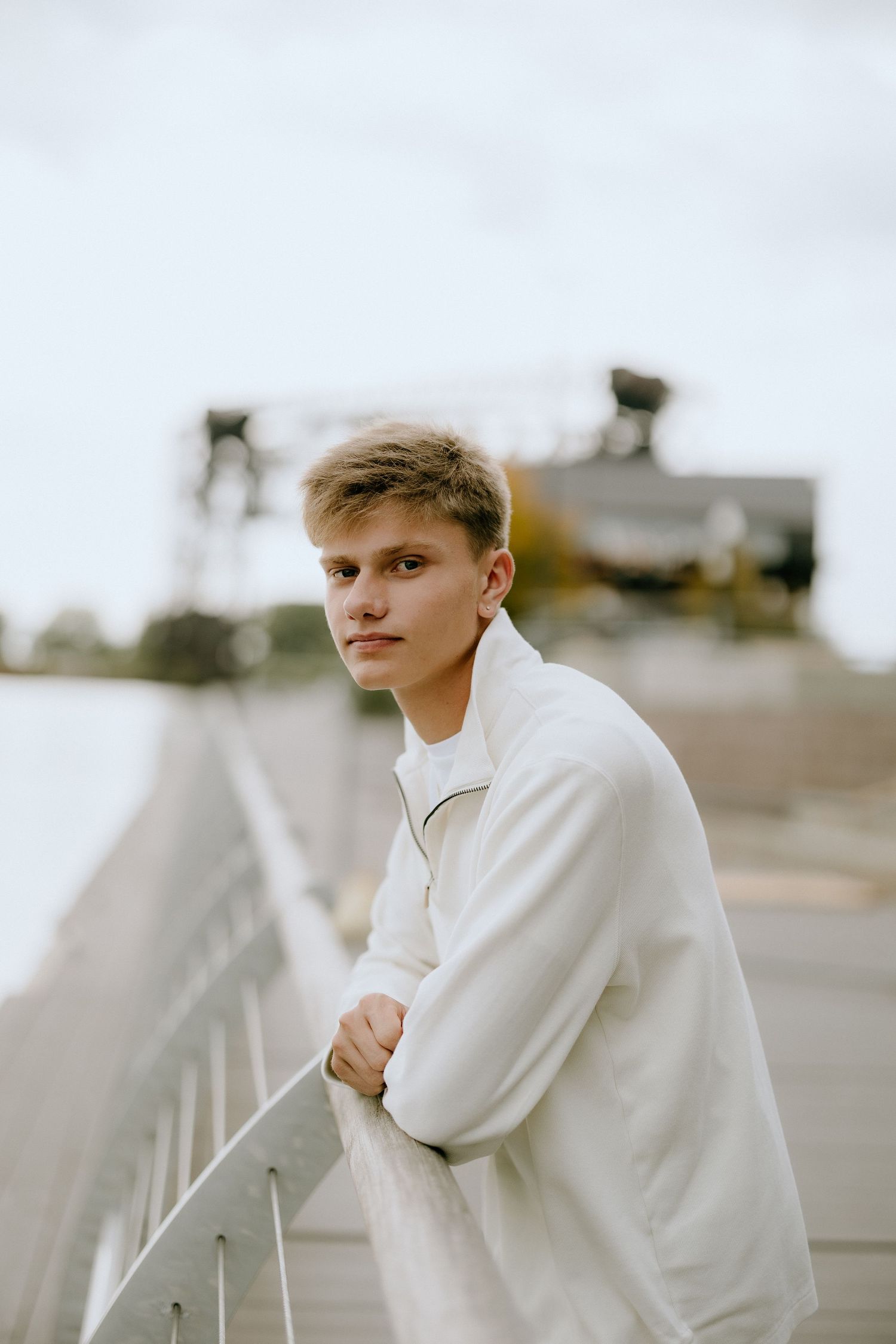 Moody portrait on bridge wearing cream colored jacket.