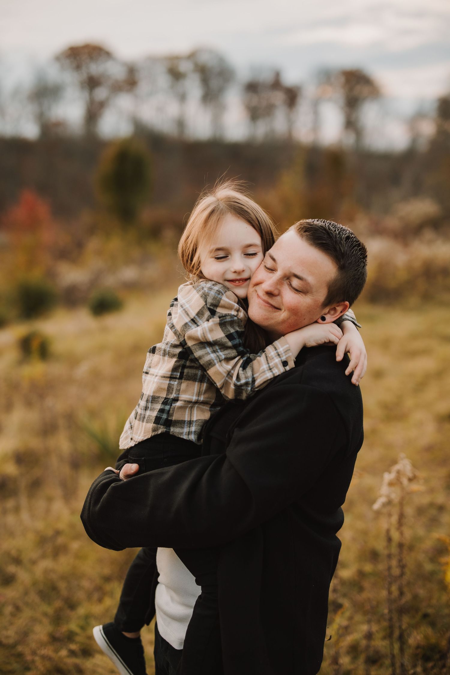 A heartwarming embrace between family members in a fall field at sunset.