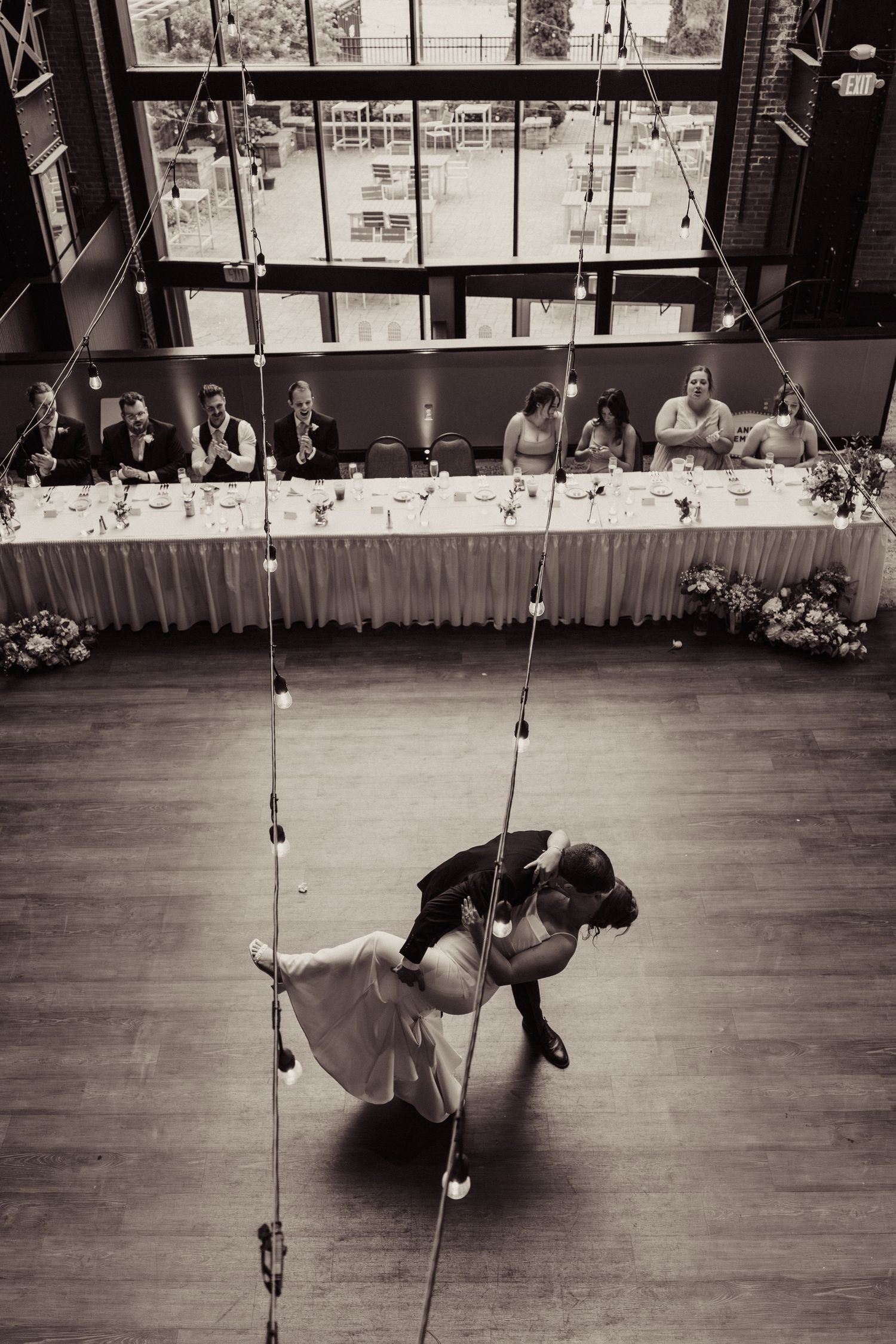 Black and white photos of a wedding dance featuring dramatic dips on a dance floor with hanging lights.