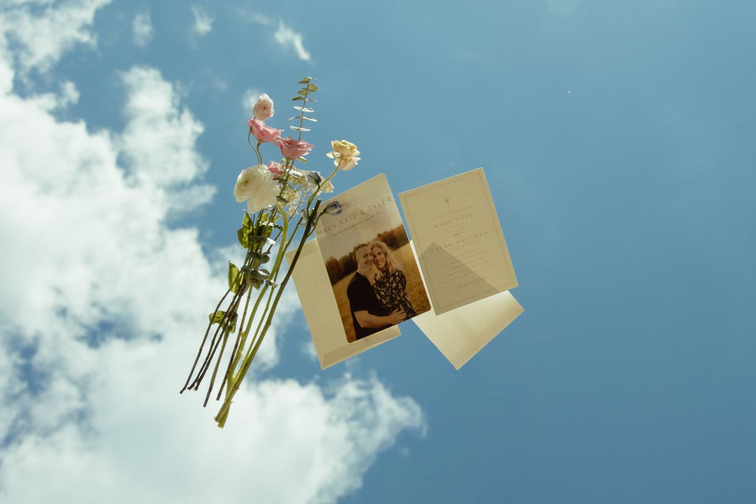 Vintage photograph and flowers floating against a blue cloudy sky in an artistic composition.