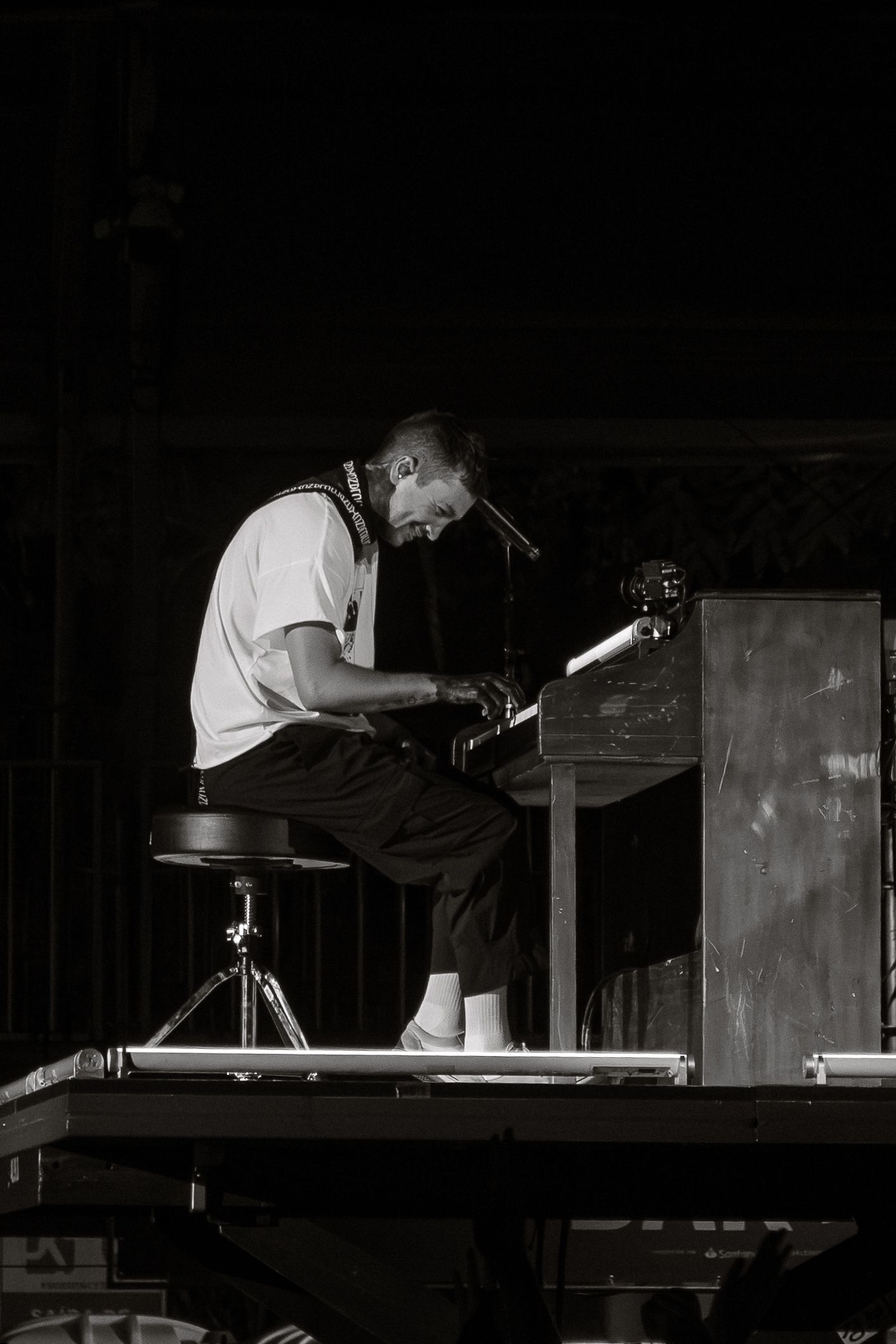 Black and white photo of musician playing piano on stage during performance.