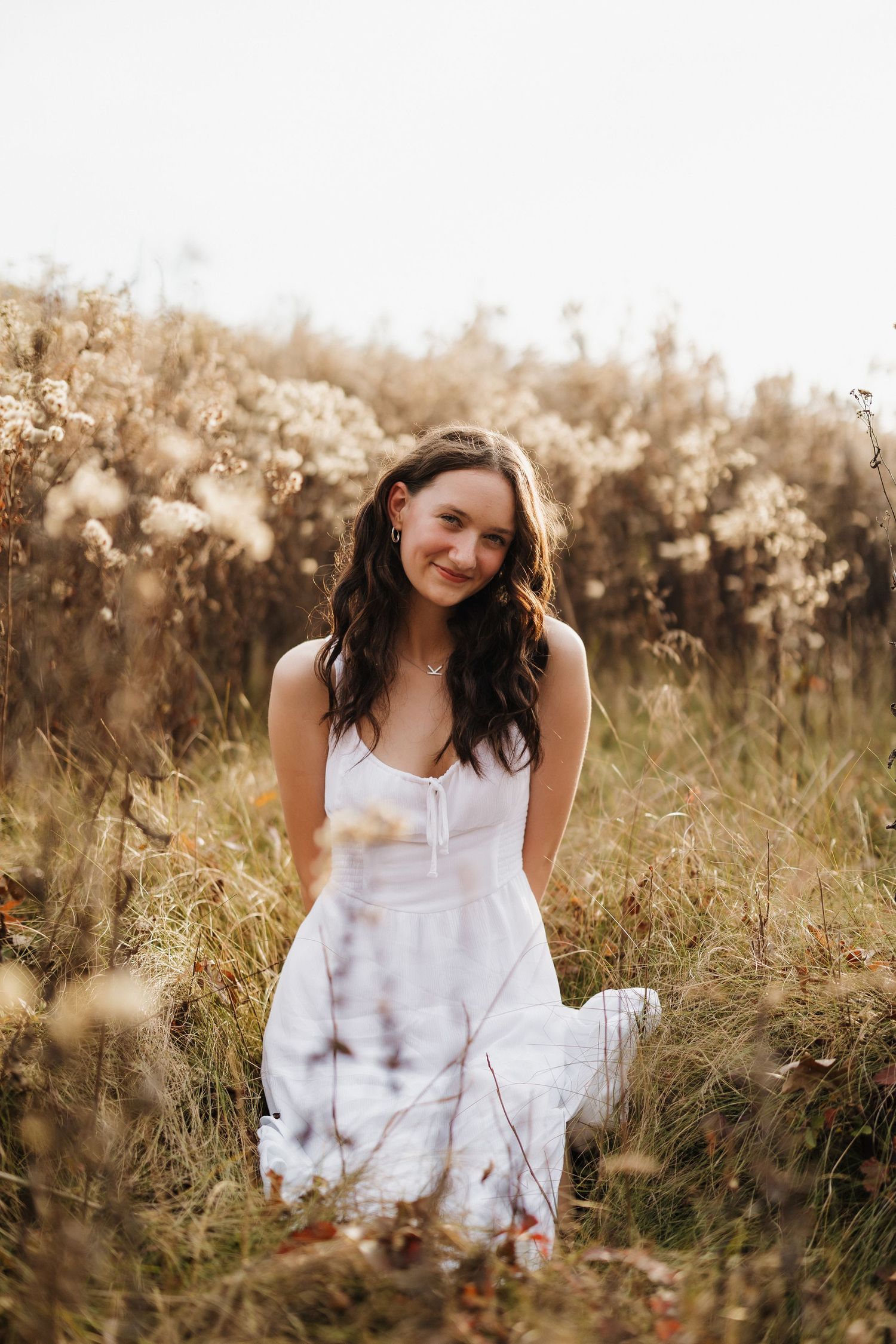 A dreamy portrait in a sun-lit field of tall grass and wildflowers.