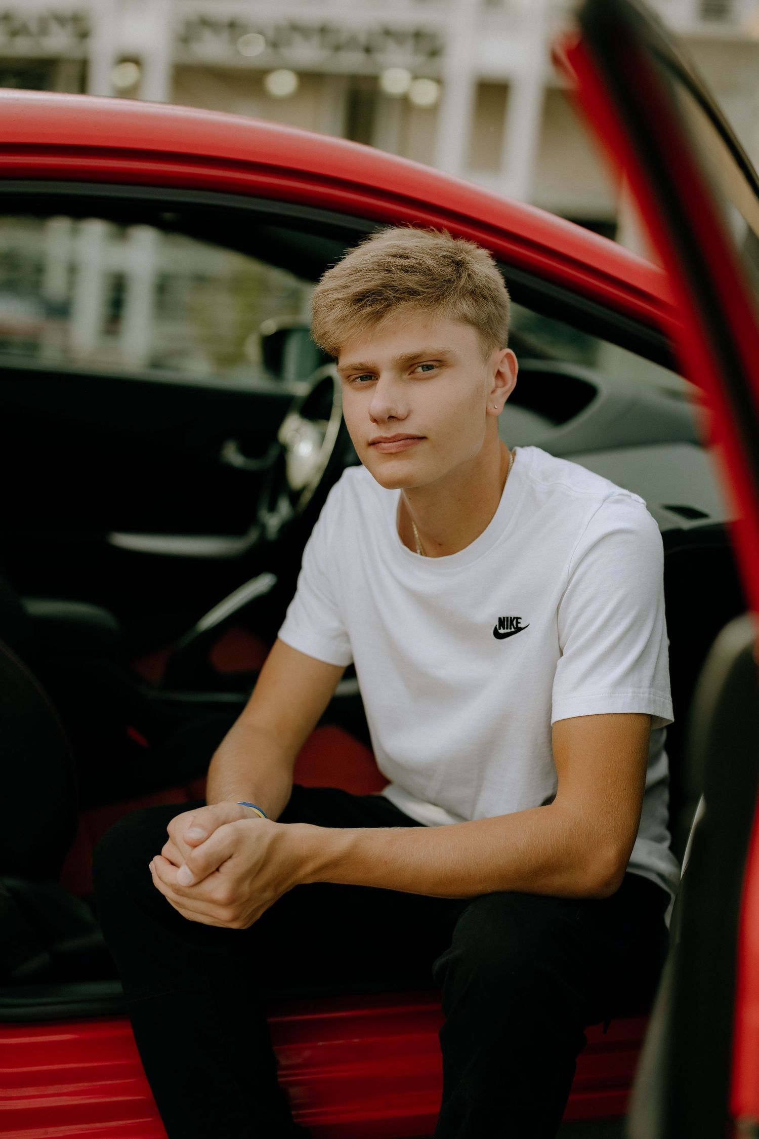 Athletic style portrait with red car wearing Nike shirt.