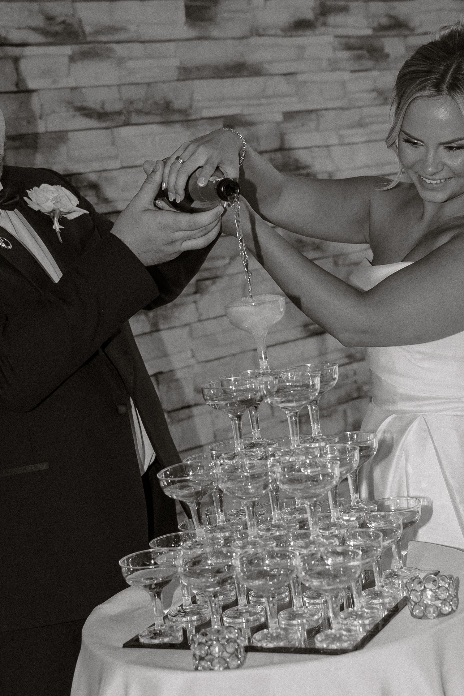 Black and white photo of champagne glasses arranged in a pyramid tower at a formal event.