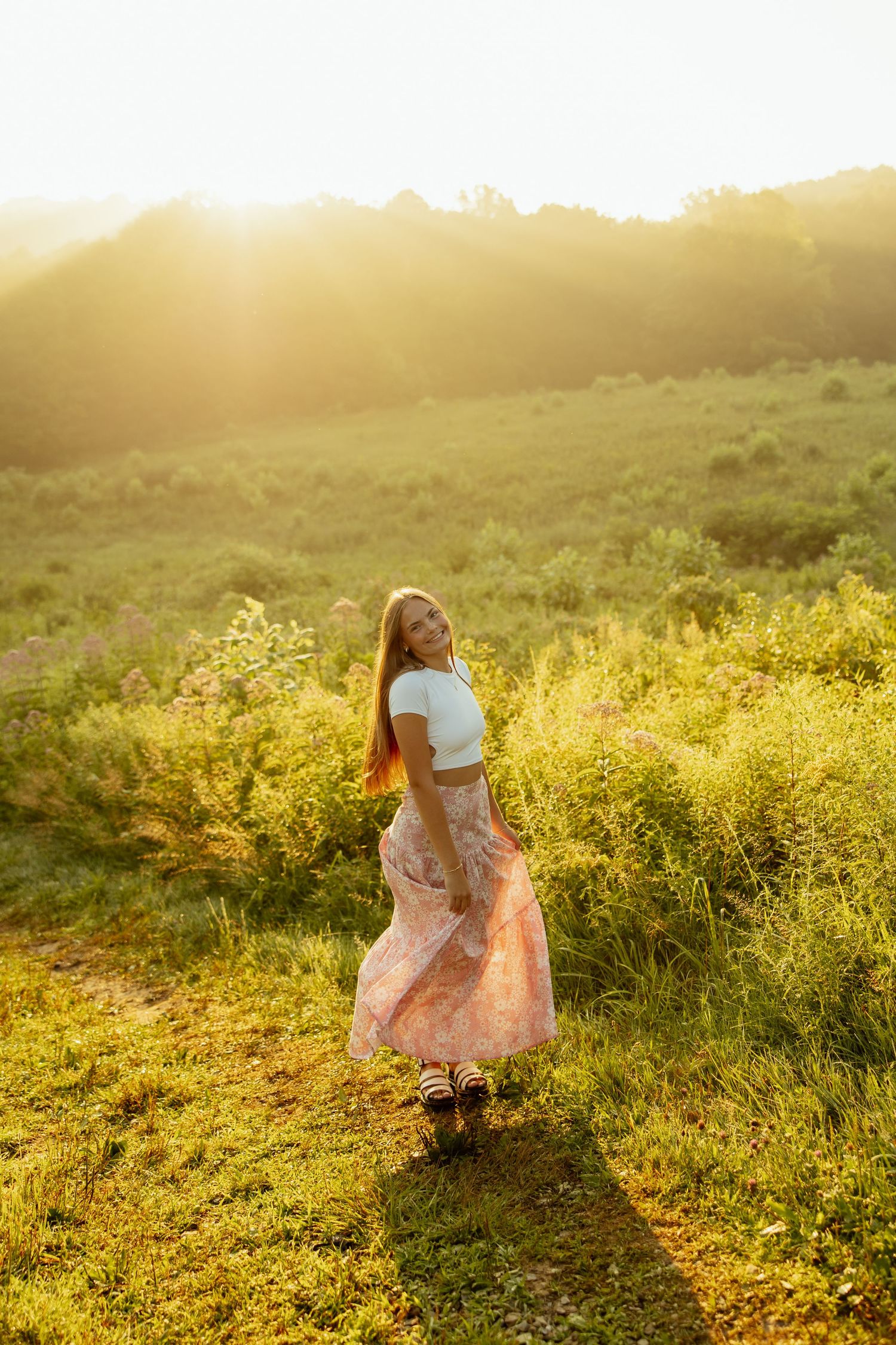 A dreamy sunset scene in a wildflower meadow with golden light filtering through the hazy atmosphere.
