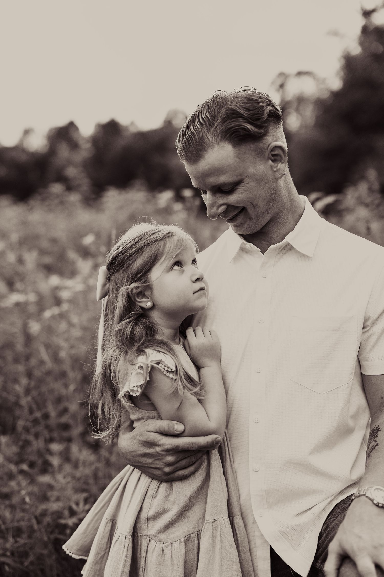 Tender black and white portrait of a child and parent sharing a loving moment outdoors.