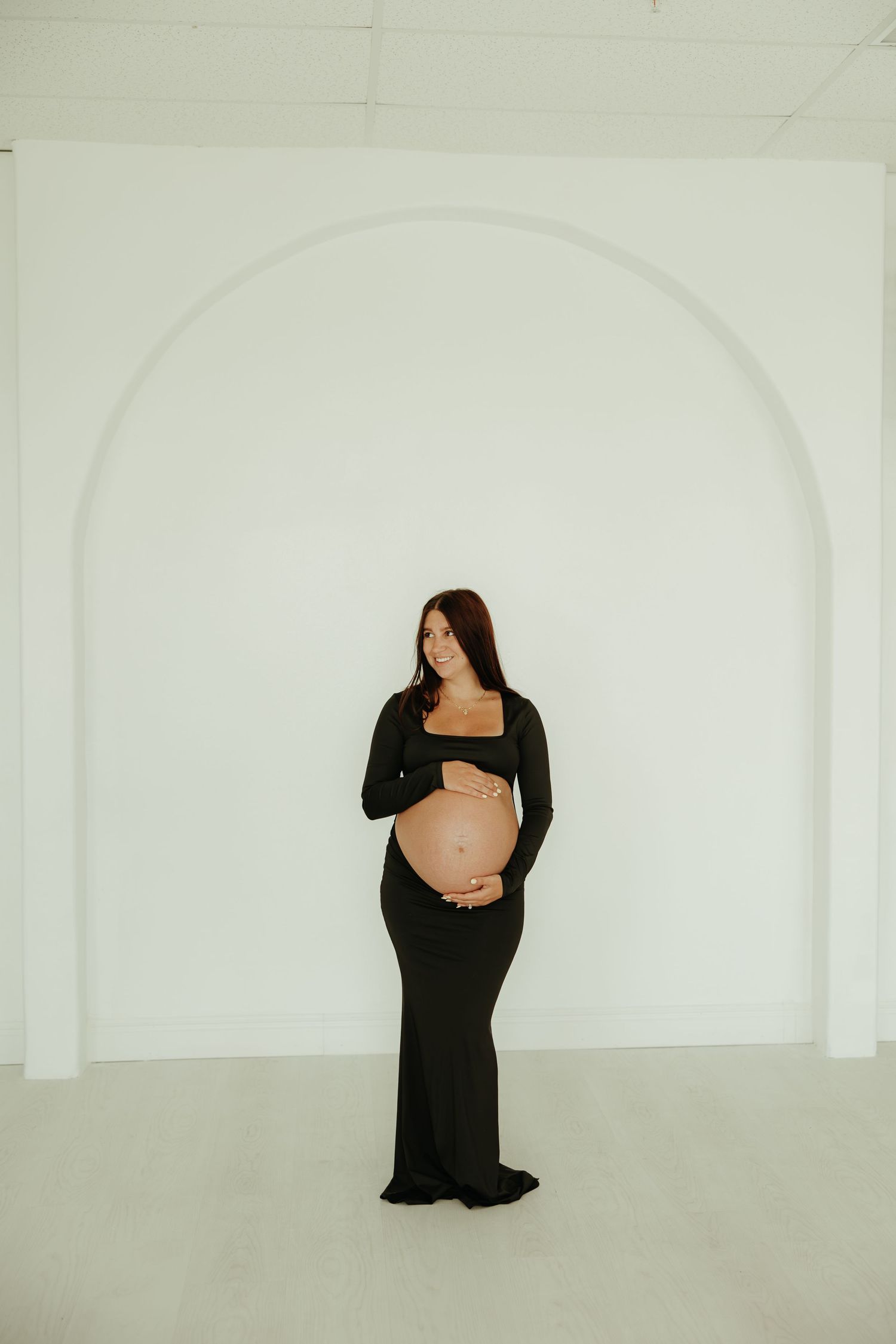 A sequence of five minimalist photos showing a figure in a black dress against a white background in different poses.