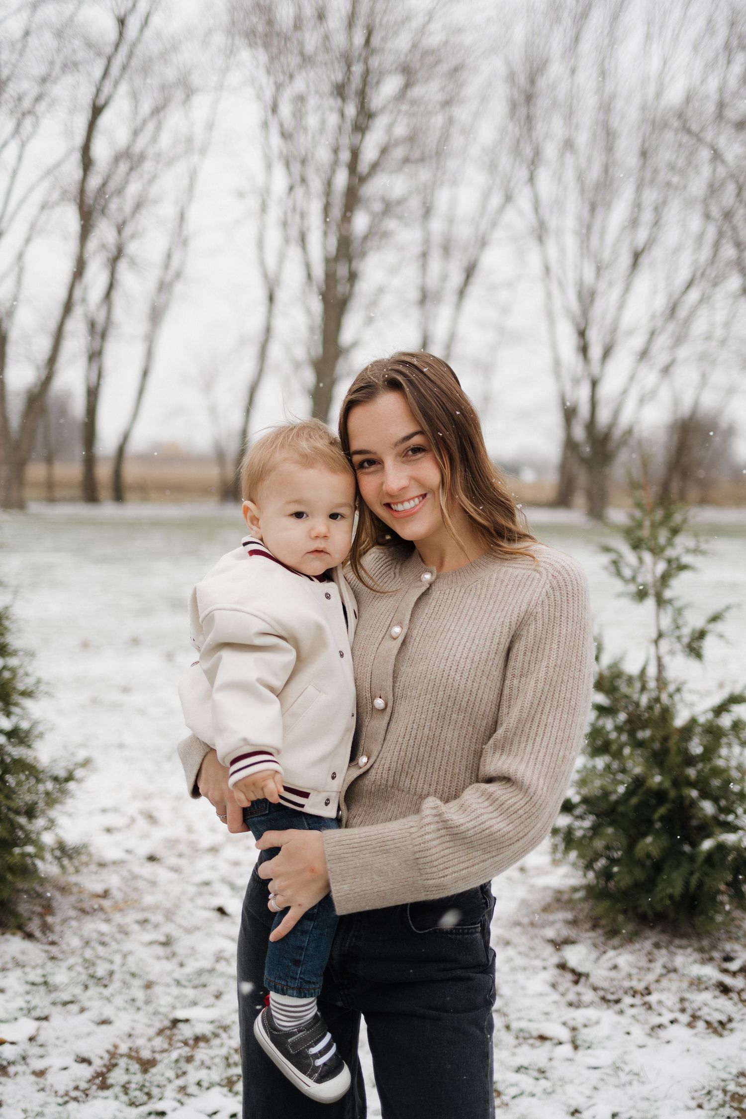 Winter portrait against bare trees with sweater-clad figures in snow.