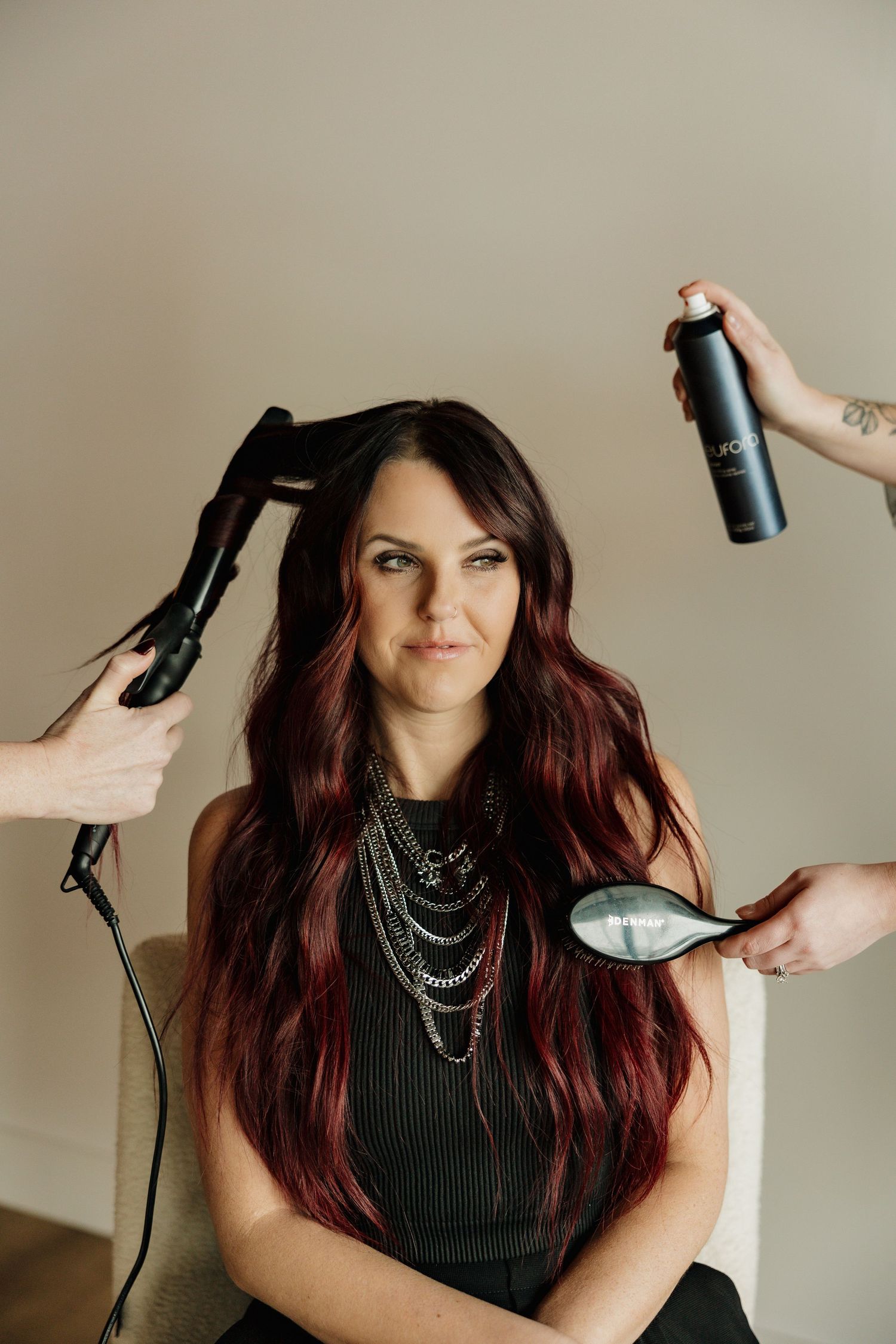 Behind-the-scenes hairstyling shot with styling tools and layered necklaces.