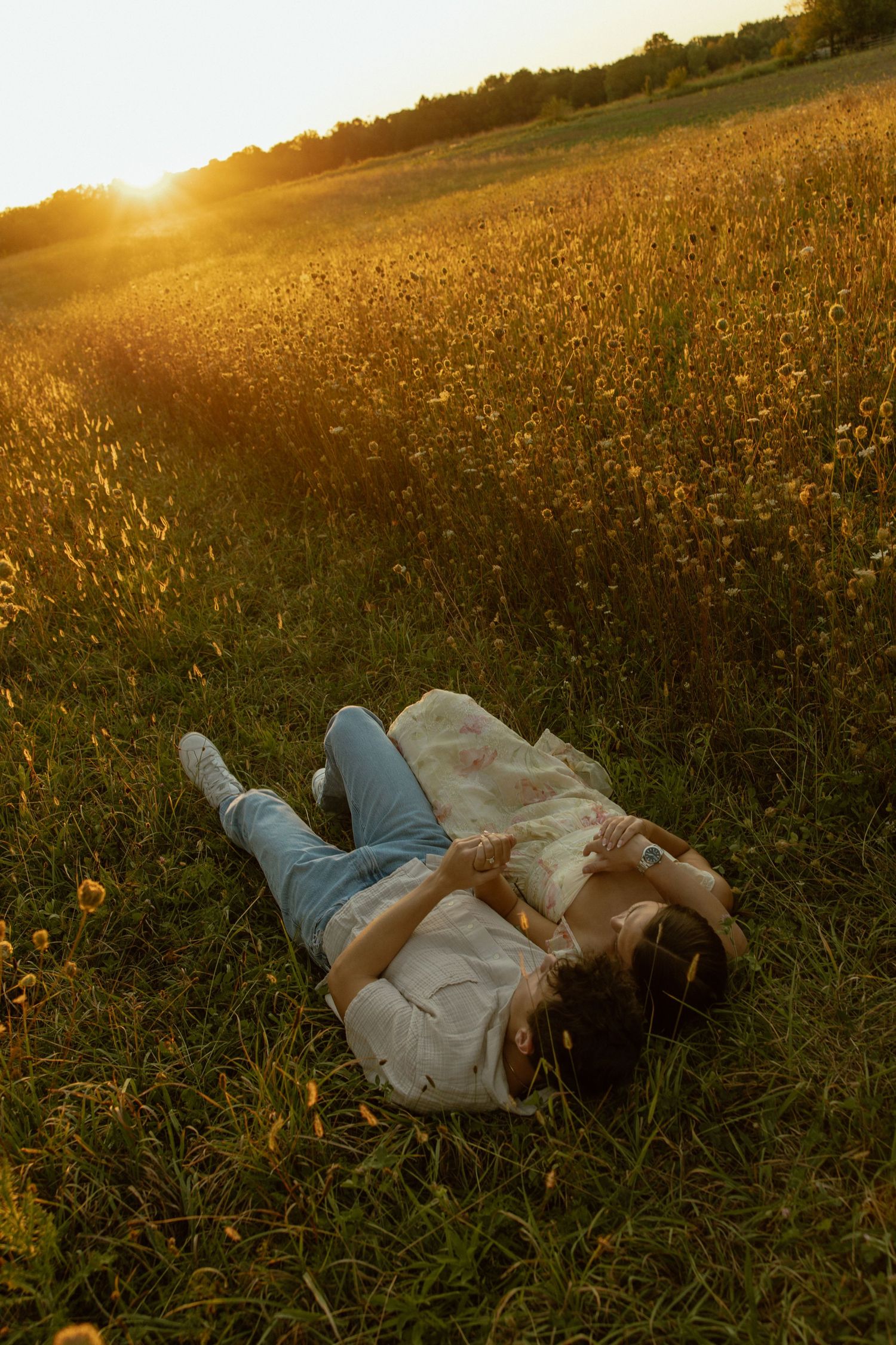 Someone lies peacefully in a golden meadow at sunset while wildflowers sway in the warm summer breeze.