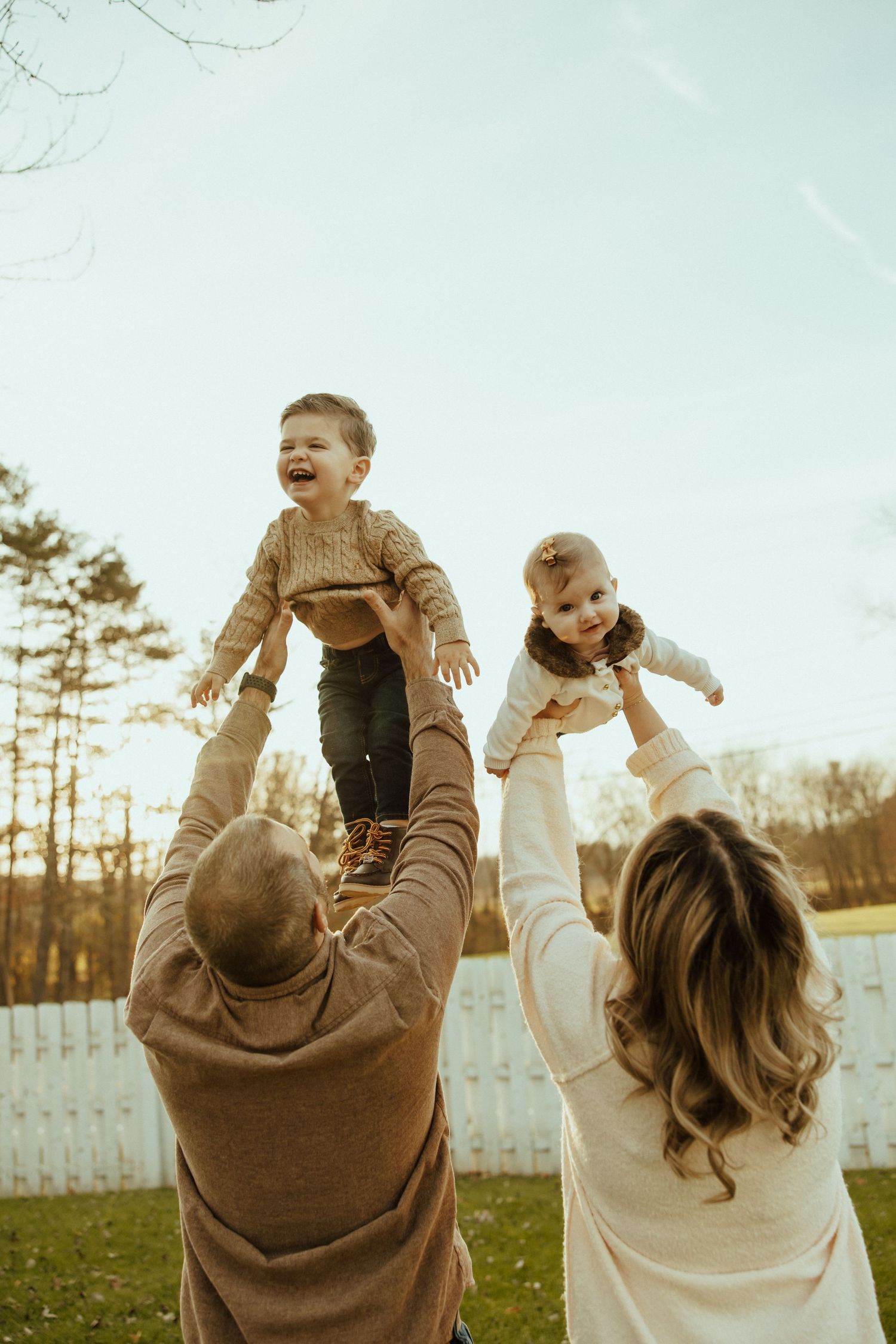 Series of joyful moments showing adults lifting babies in the air against a backyard setting at sunset.