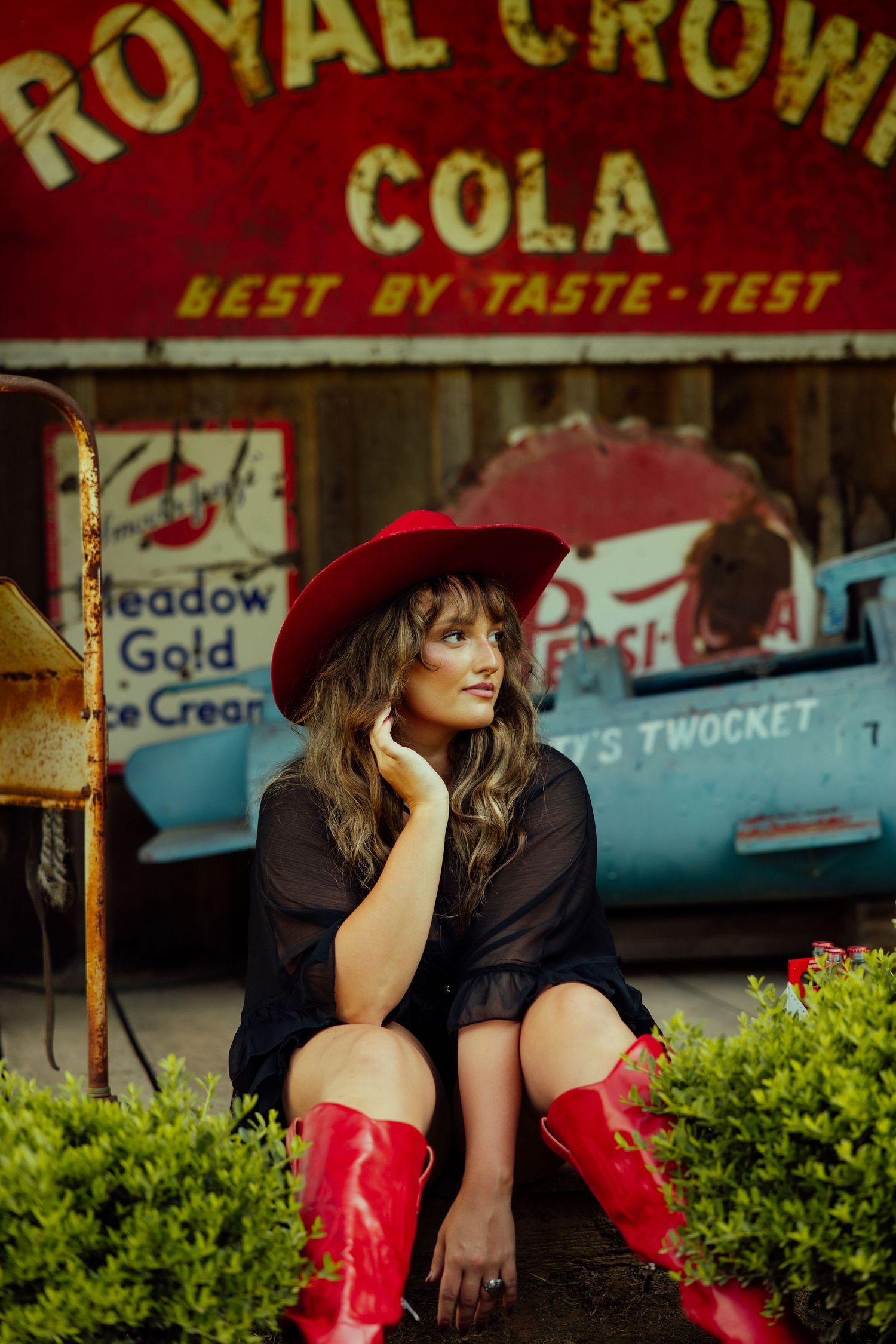 A vintage-style photo at a retro Royal Crown Cola storefront with red cowboy boots and a burgundy hat.