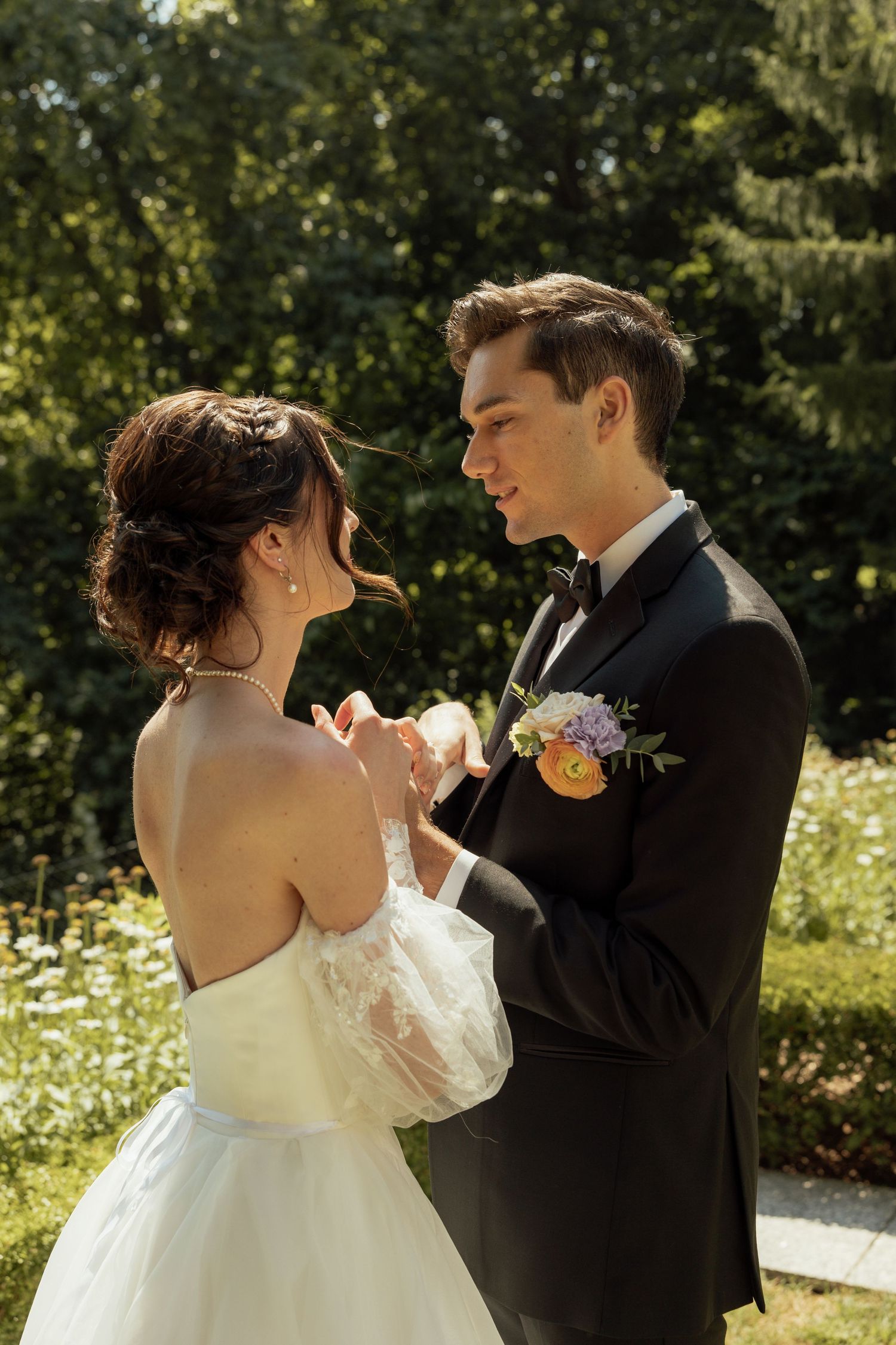 A couple shares an intimate dance moment in a sun-dappled garden setting.