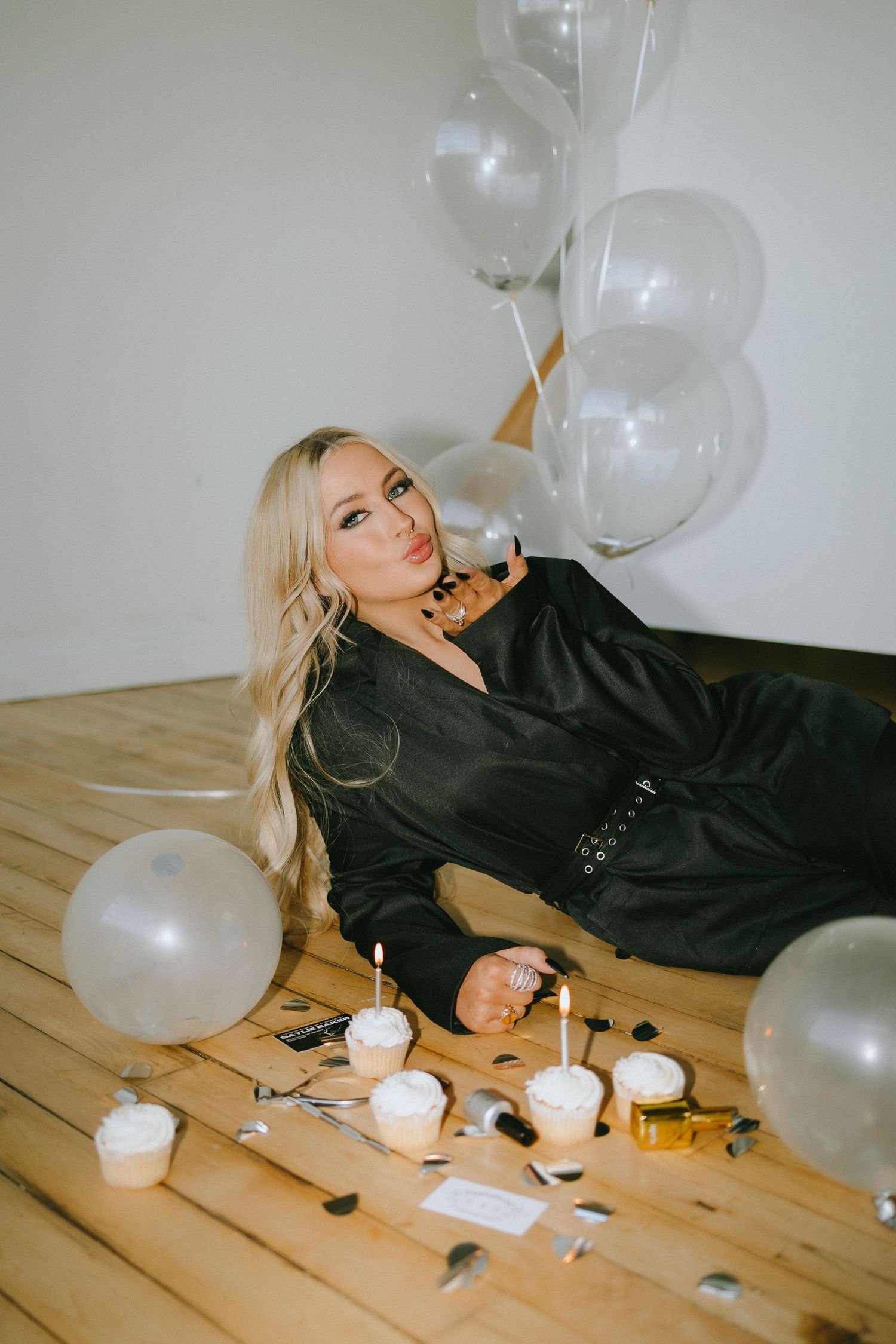 Artistic photo with white balloons and scattered props on hardwood floor.