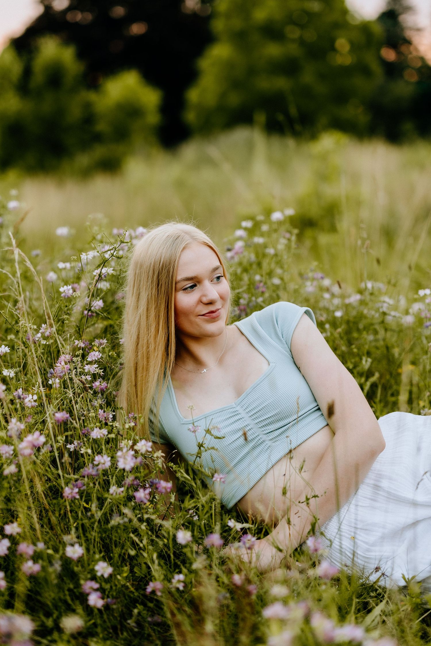 Summer portrait laying in blooming wildflower field wearing mint green top.