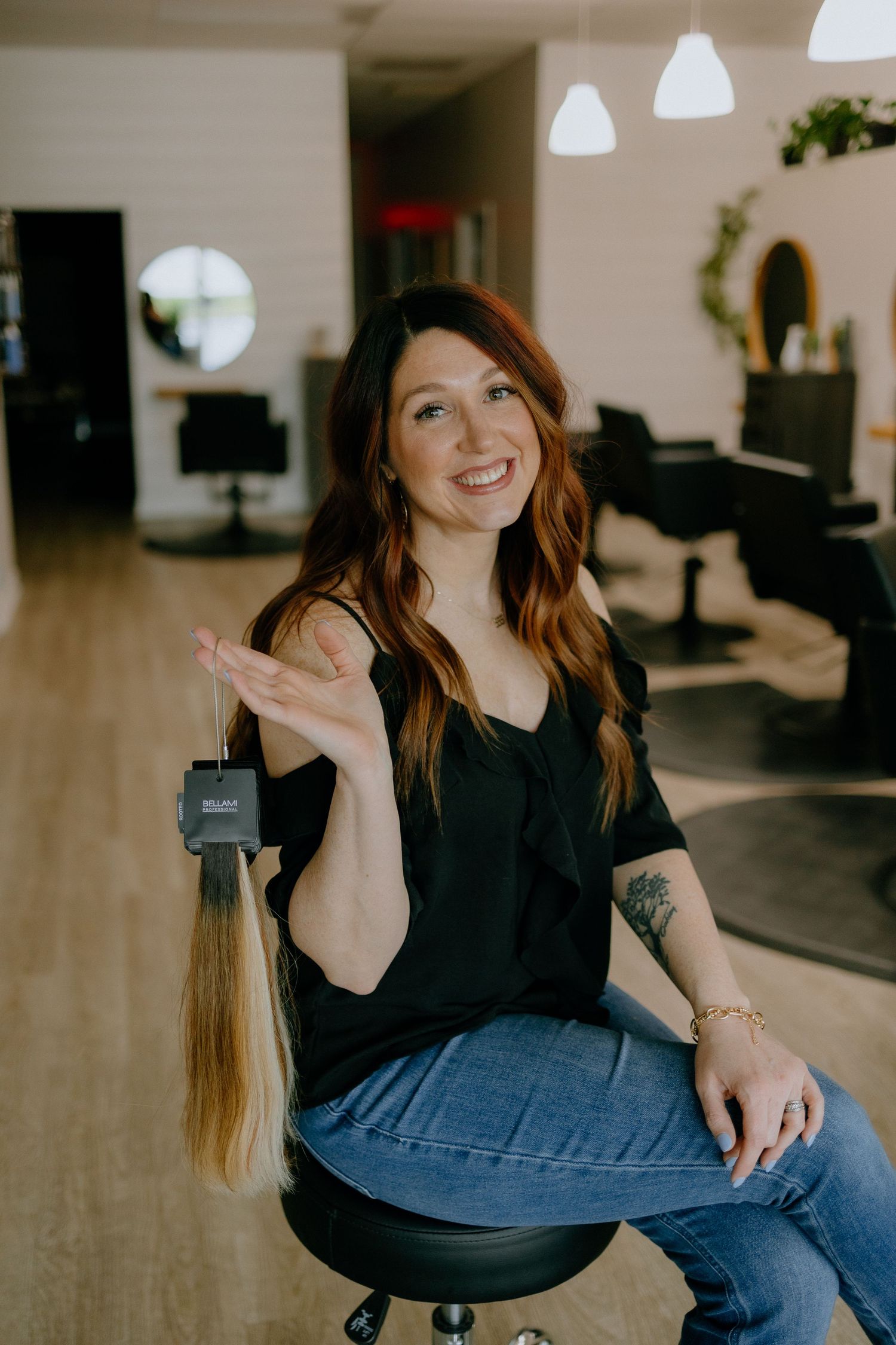 Person in black top and jeans sits on salon chair in modern salon interior.