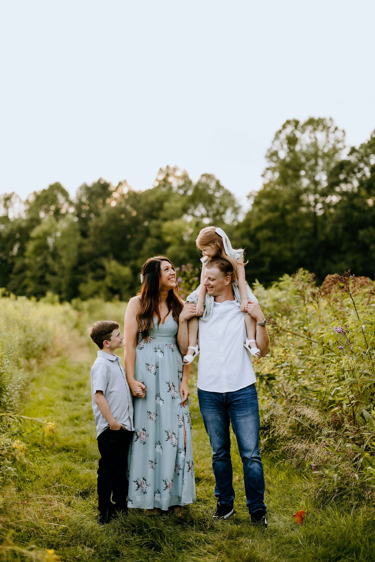 Family of four enjoying time together in meadow during golden hour.