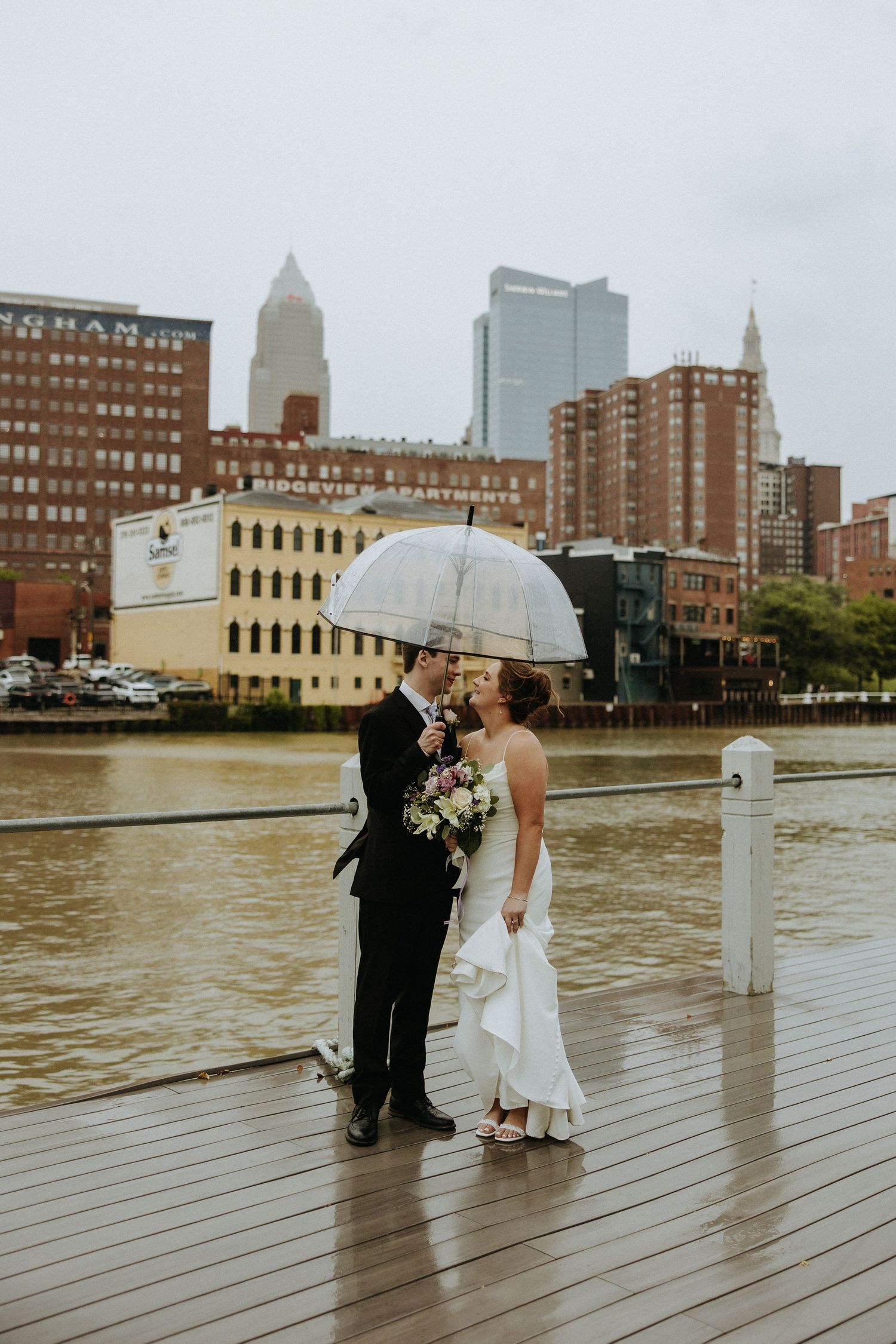 Romantic wedding photos on a waterfront deck with city skyline in the background.