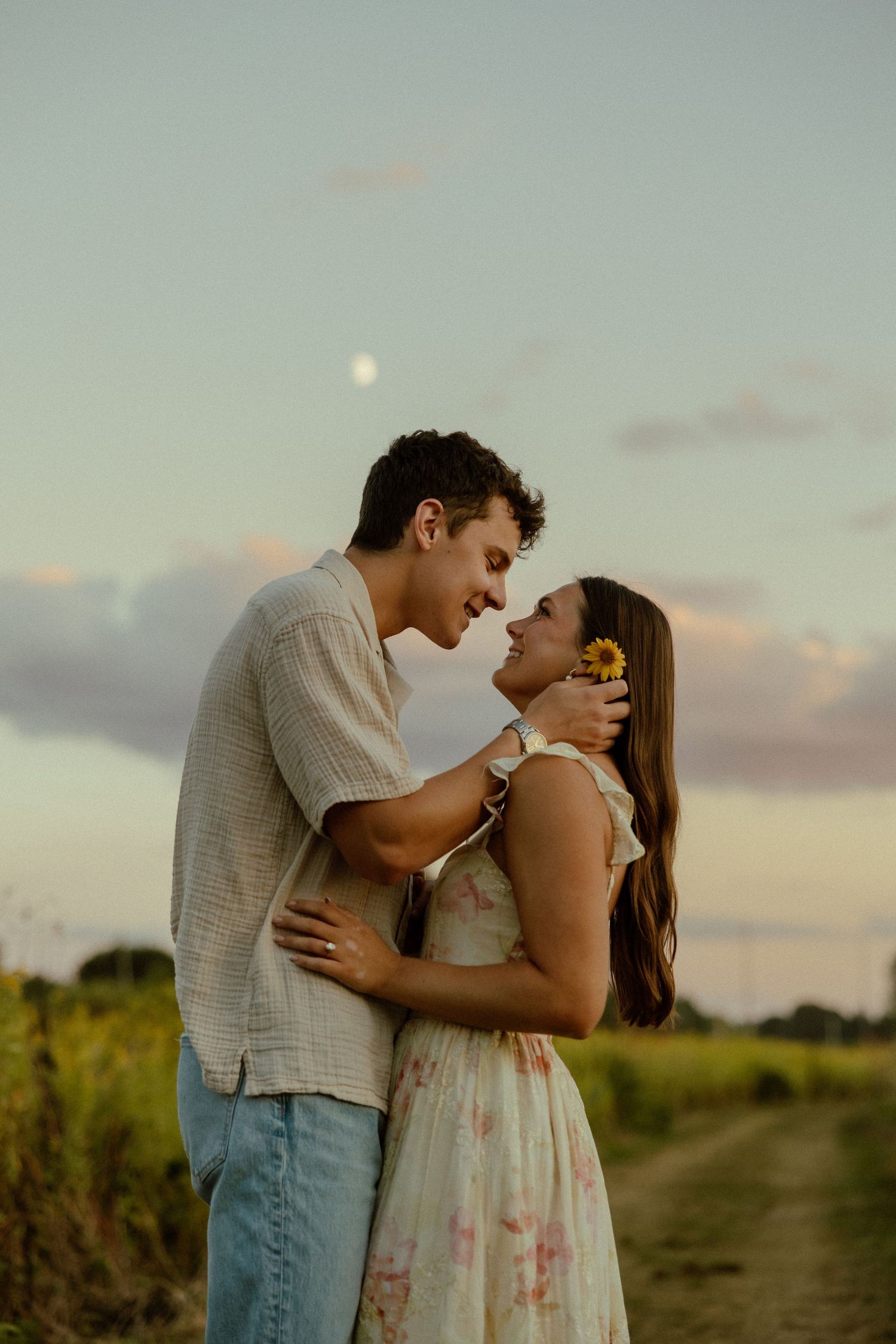A romantic couple embraces in a golden field at sunset with soft lighting and dreamy atmosphere.