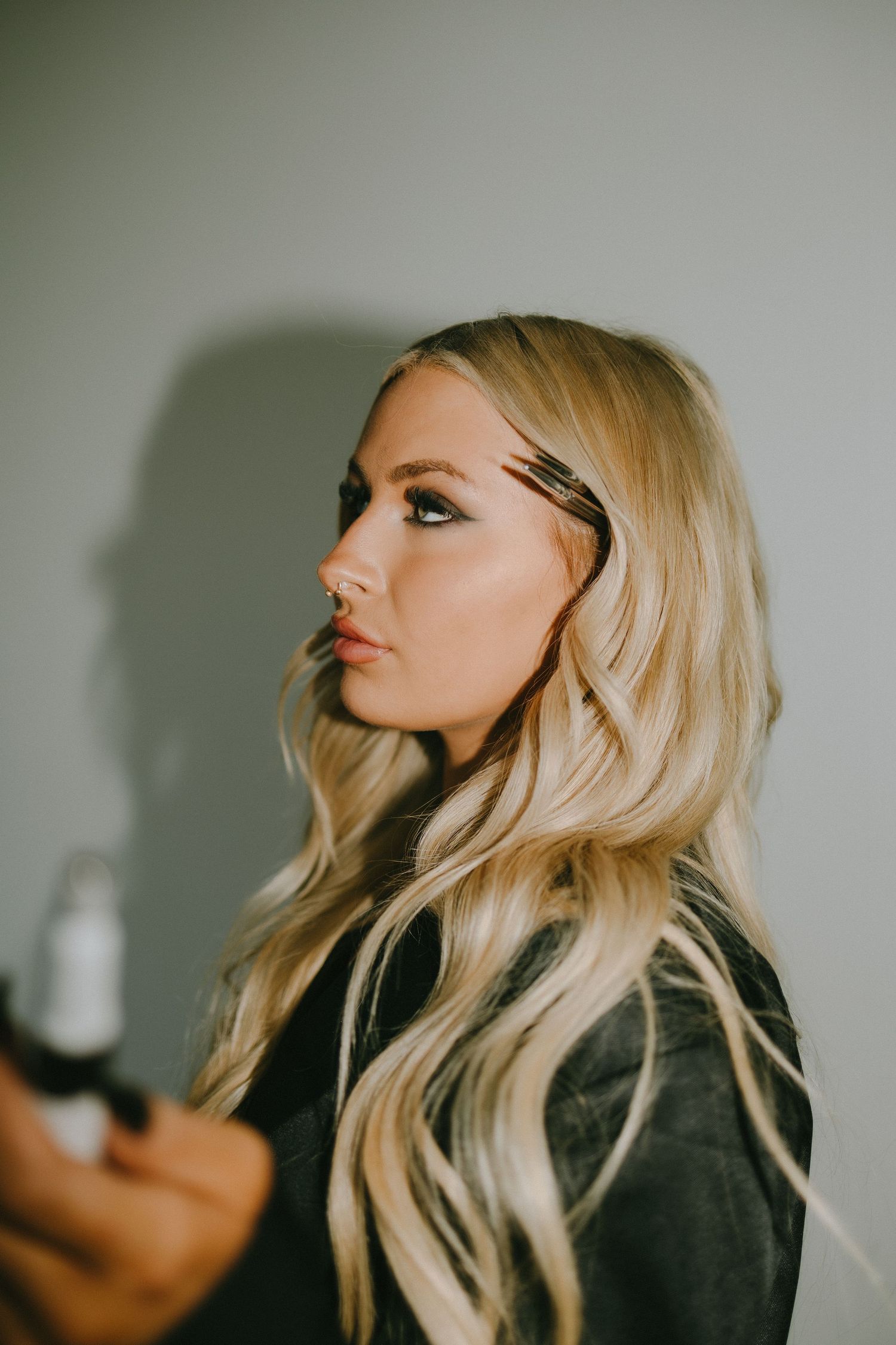Side profile portrait with flowing blonde waves and dramatic eye makeup.