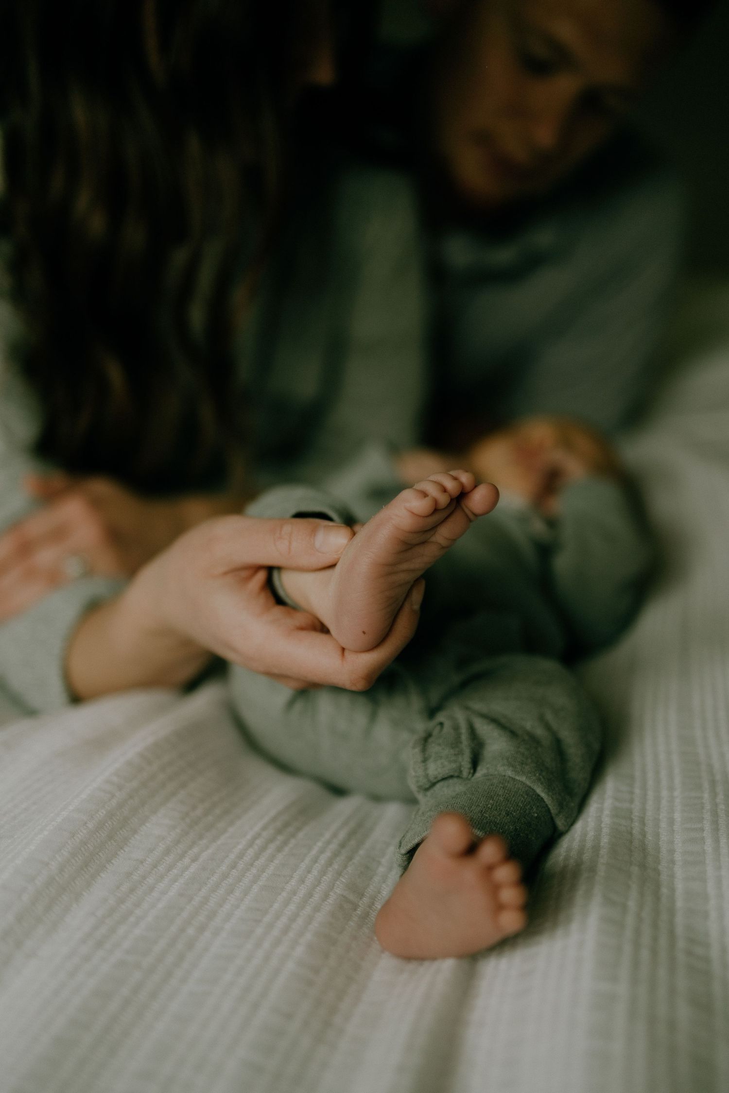 Close-up view of tiny baby feet being gently held on a textured white surface.