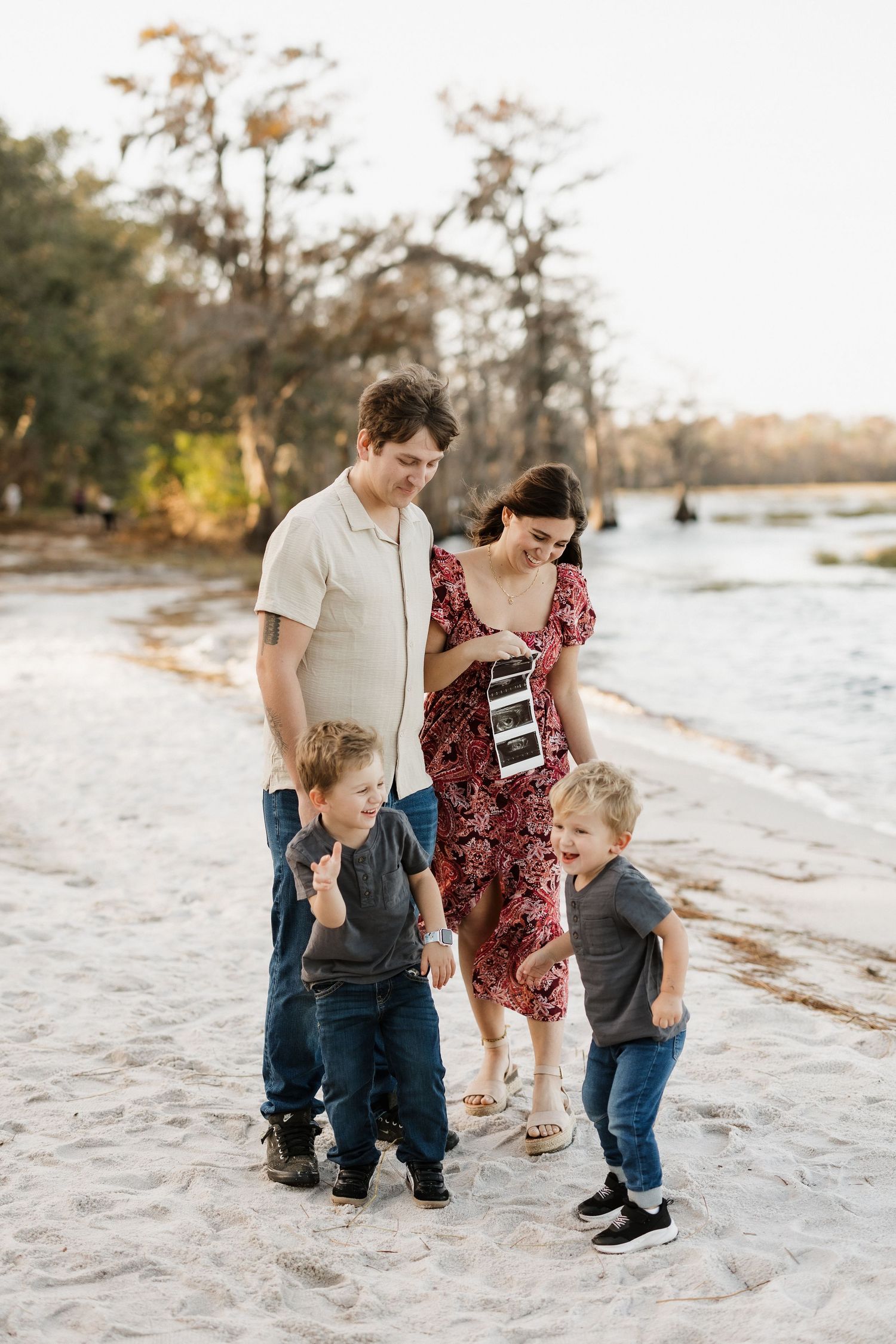 Family walking on beach together while looking at ultrasound photos.