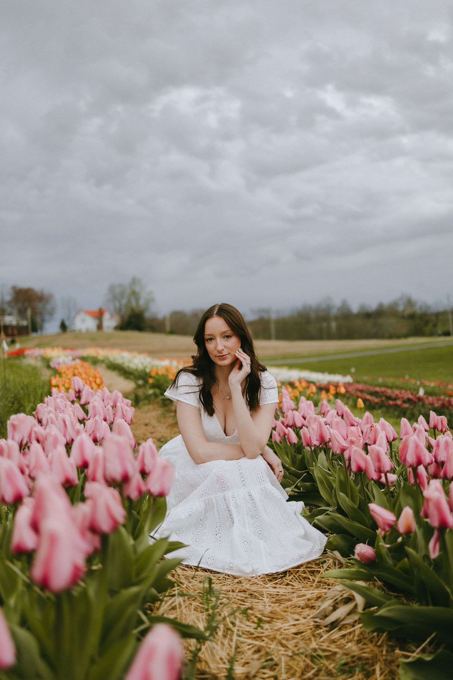 Portrait session with white dress among pink tulips on a cloudy spring day.