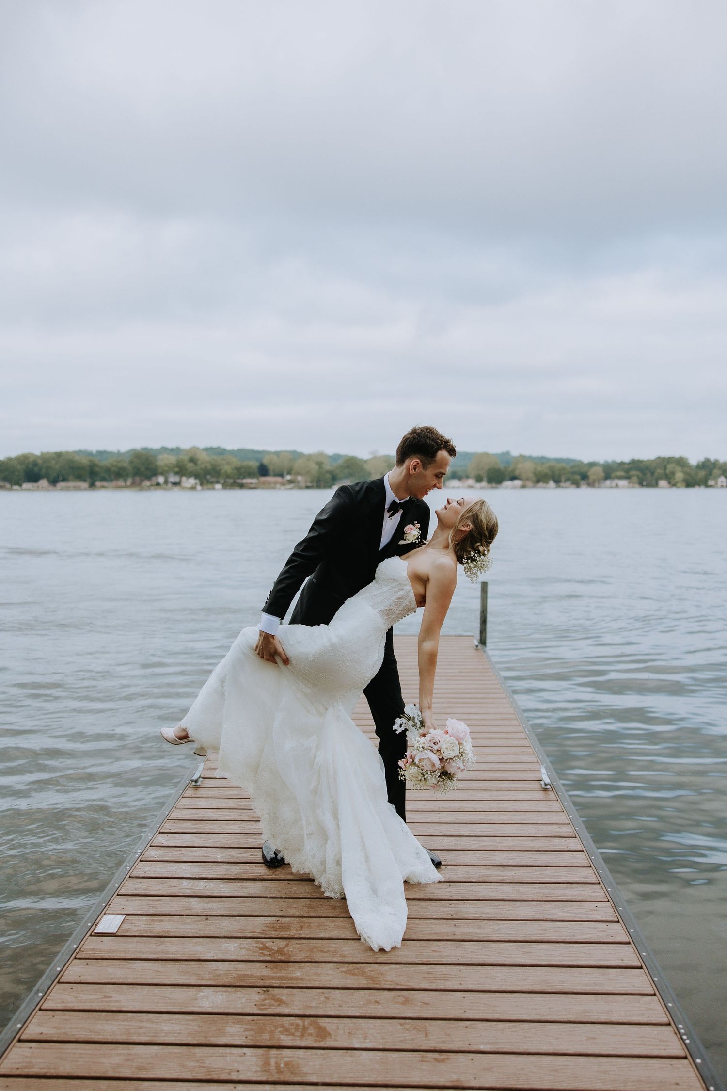 A romantic wedding photo sequence showing a couple dipping pose on a wooden dock by a lake.