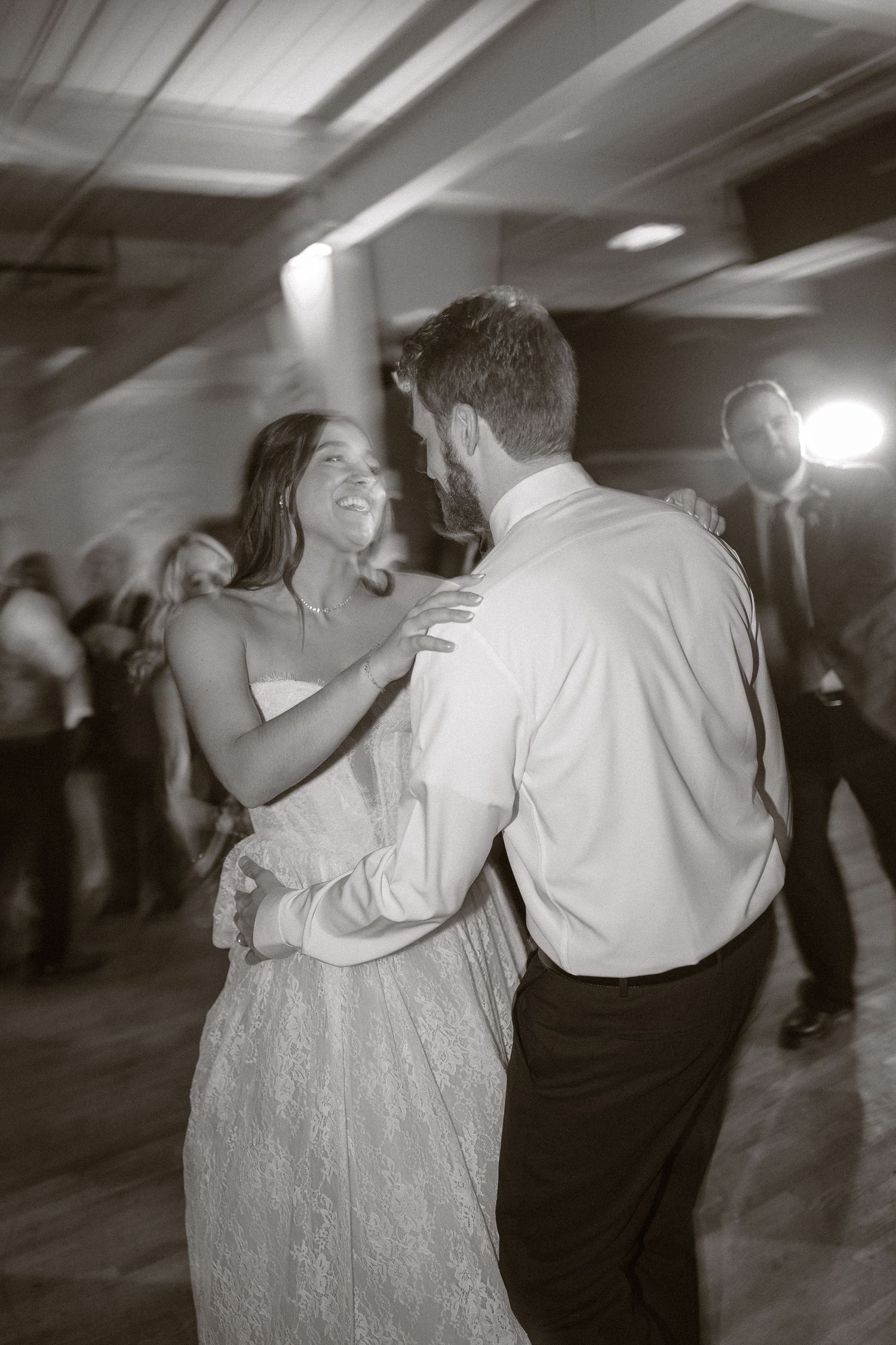A black and white photo capturing a joyful moment of newlyweds dancing at their wedding reception.