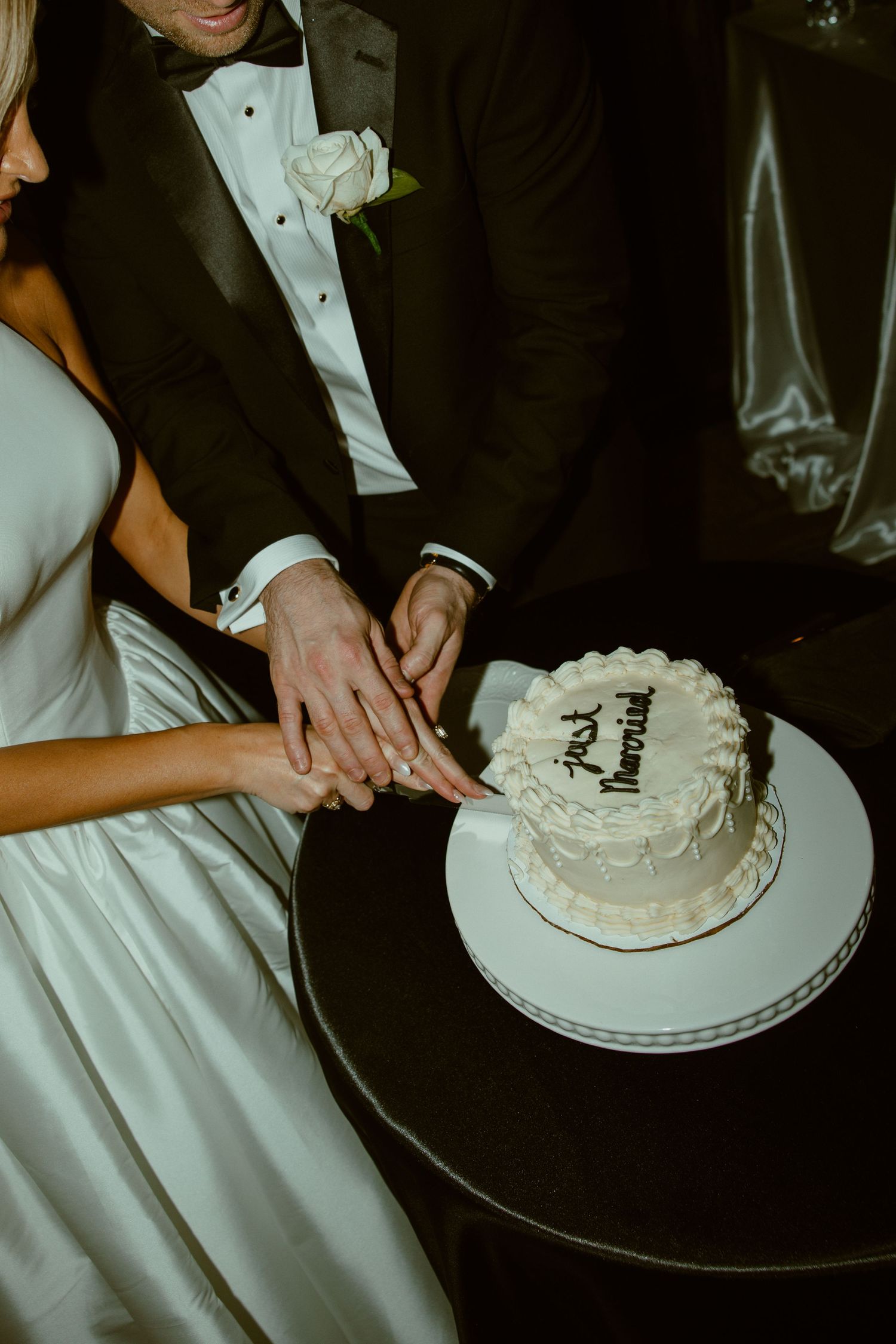 Newlyweds cutting their white wedding cake together during the reception celebration.