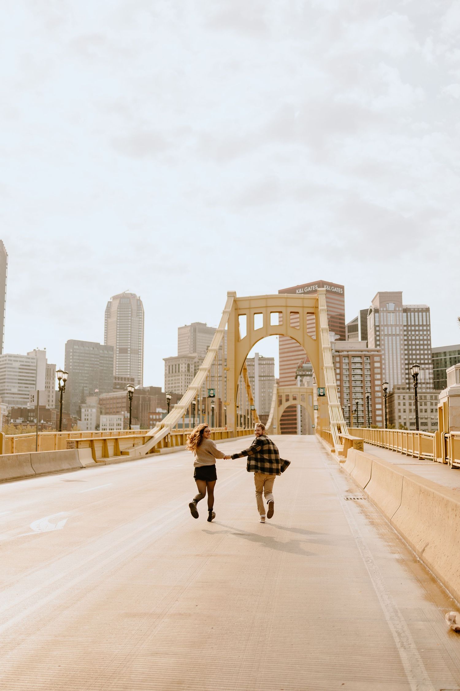 Two people walk hand in hand across Pittsburgh's iconic yellow bridge.