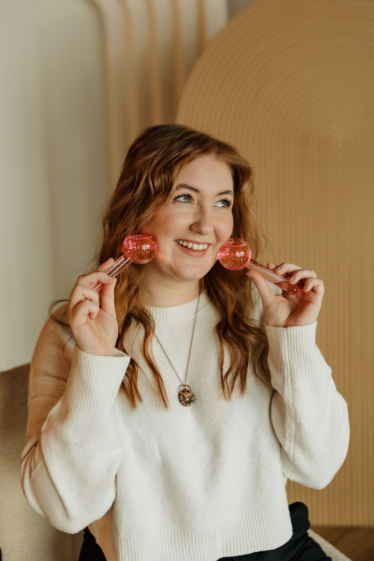 Cheerful winter portrait holding red lollipops against a geometric wall backdrop.