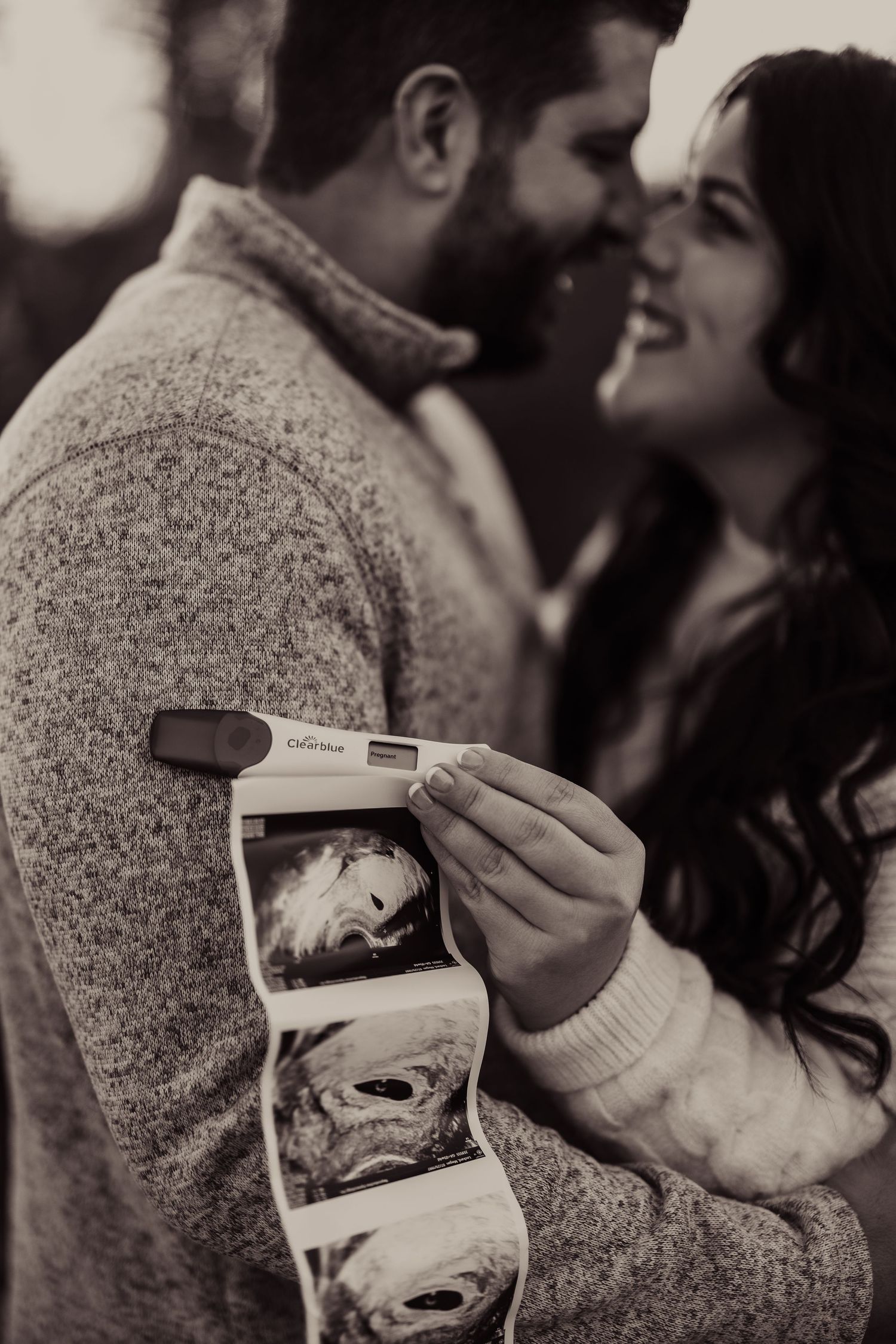 Couple looking at ultrasound photos together in a romantic black and white moment.