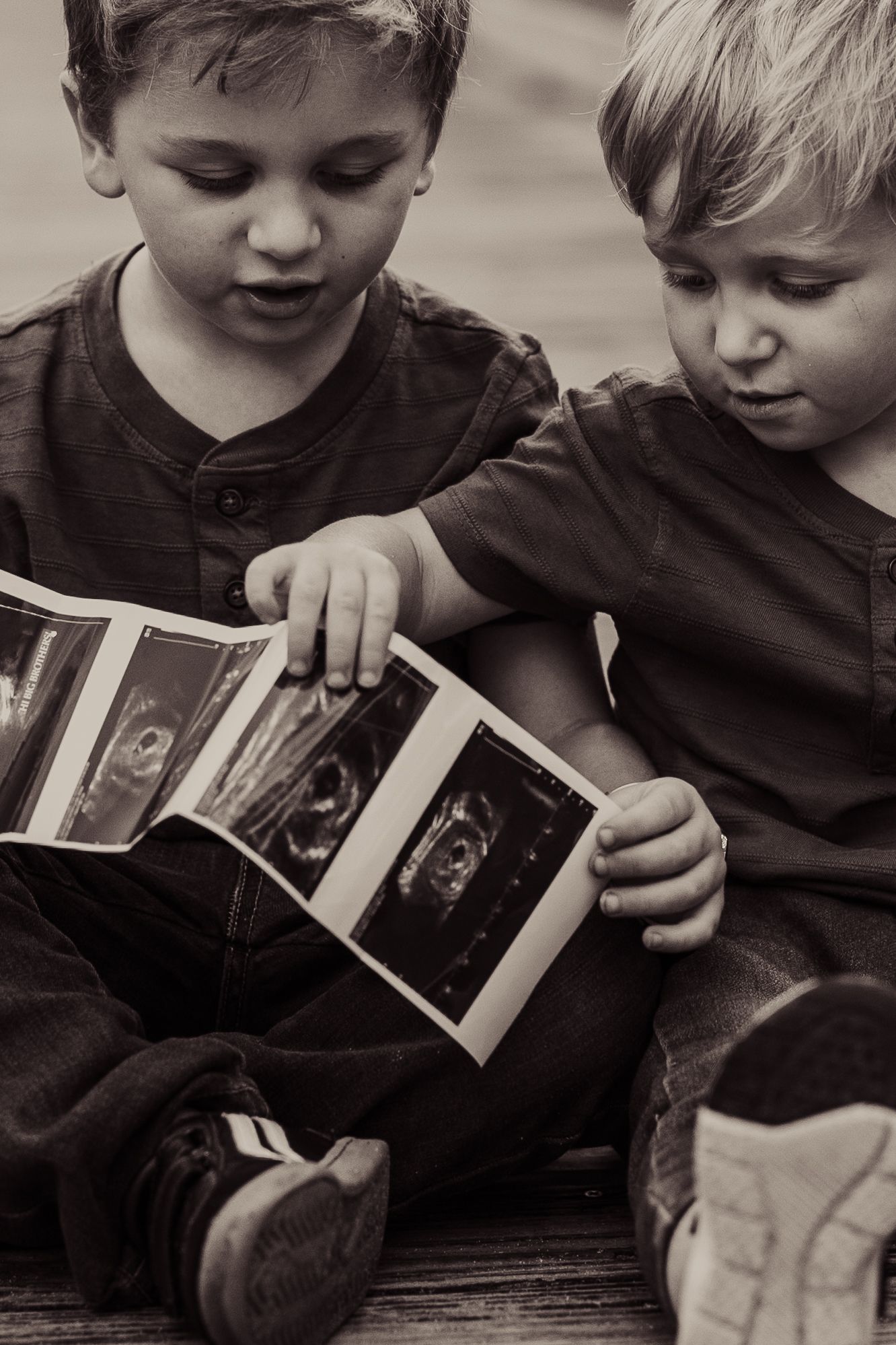 Black and white photo of two children looking at ultrasound strip together.