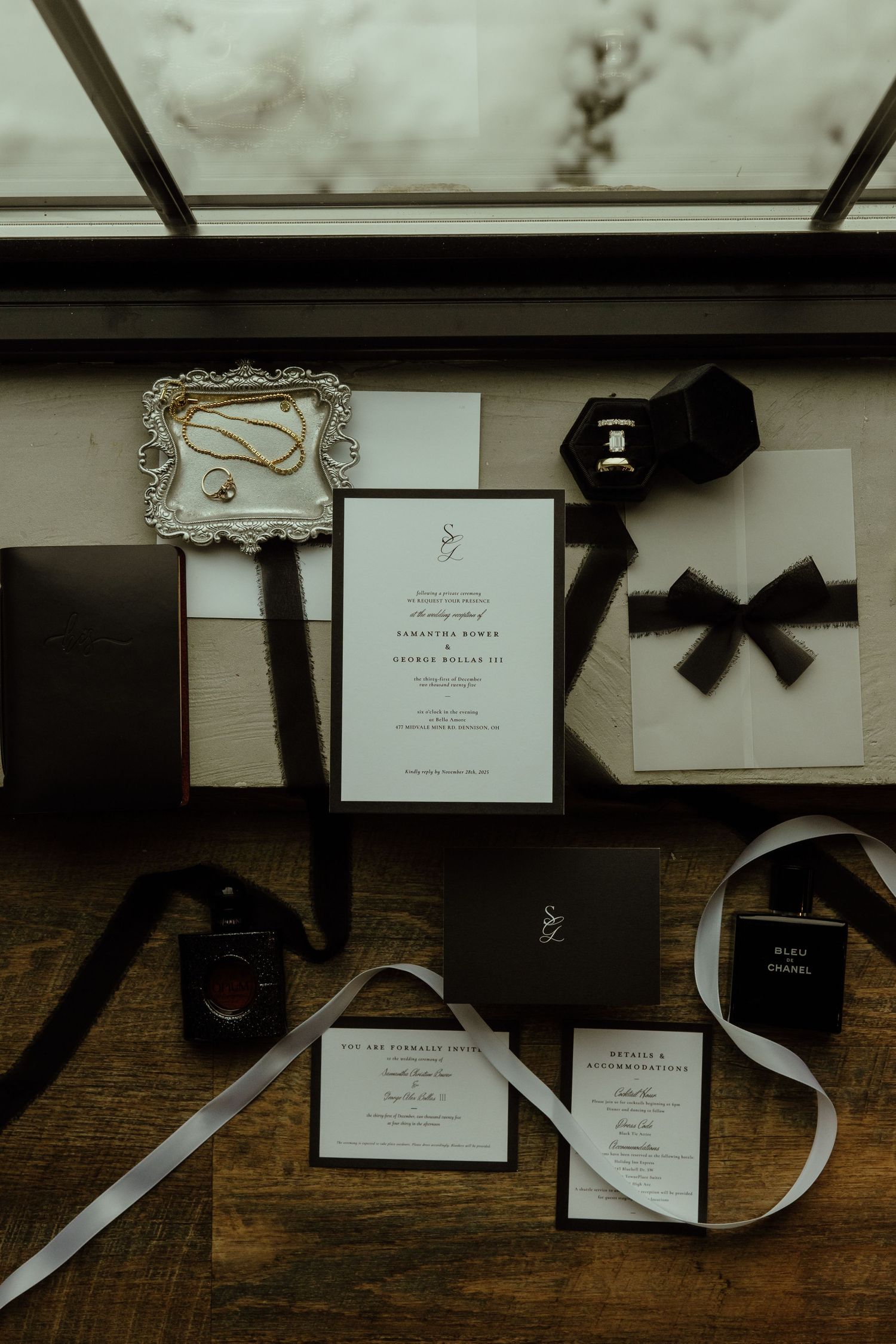 Elegant black and white wedding invitations and stationery with ribbons arranged on a rustic wooden surface.