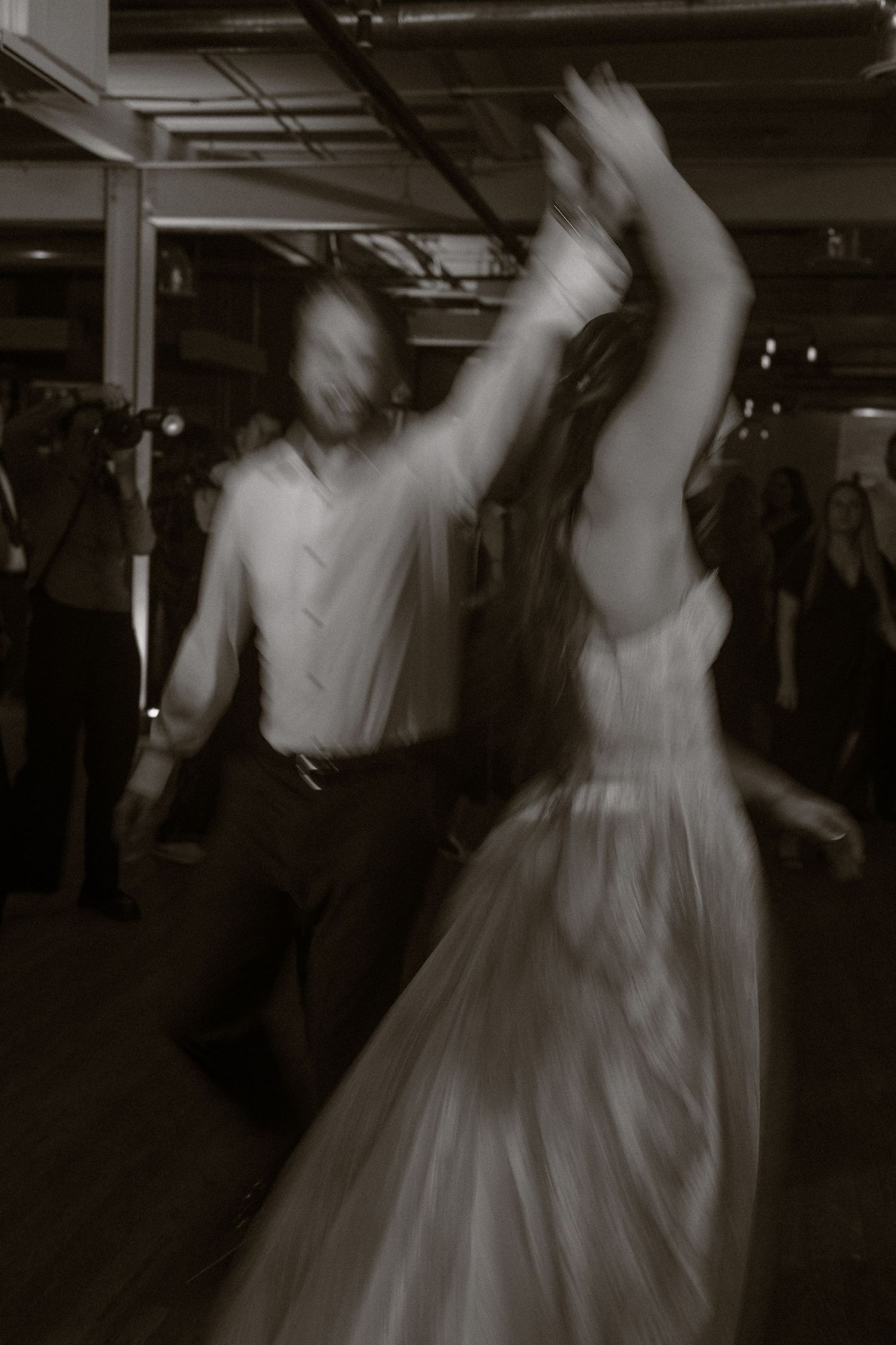 Motion-blurred black and white photos of wedding dance floor with spinning white dress.