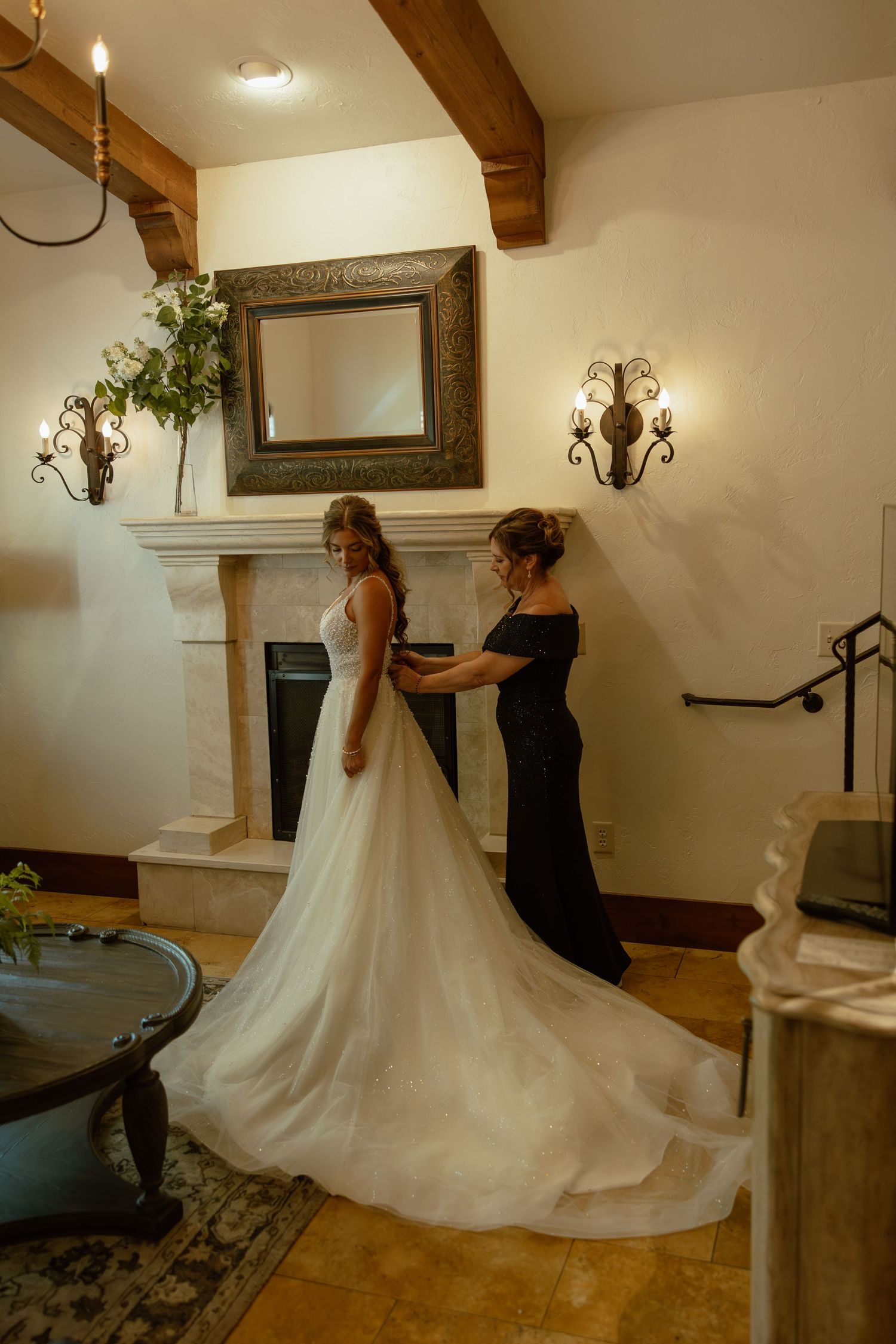 A sequence showing the back of a wedding dress being fitted and arranged in an elegant indoor setting.