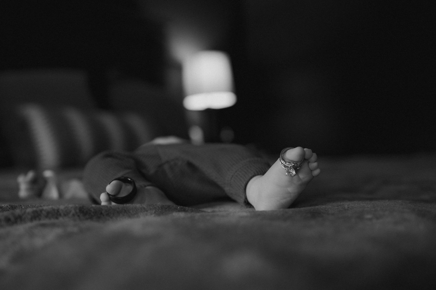 Artistic black and white photograph of small baby feet against textured fabric.