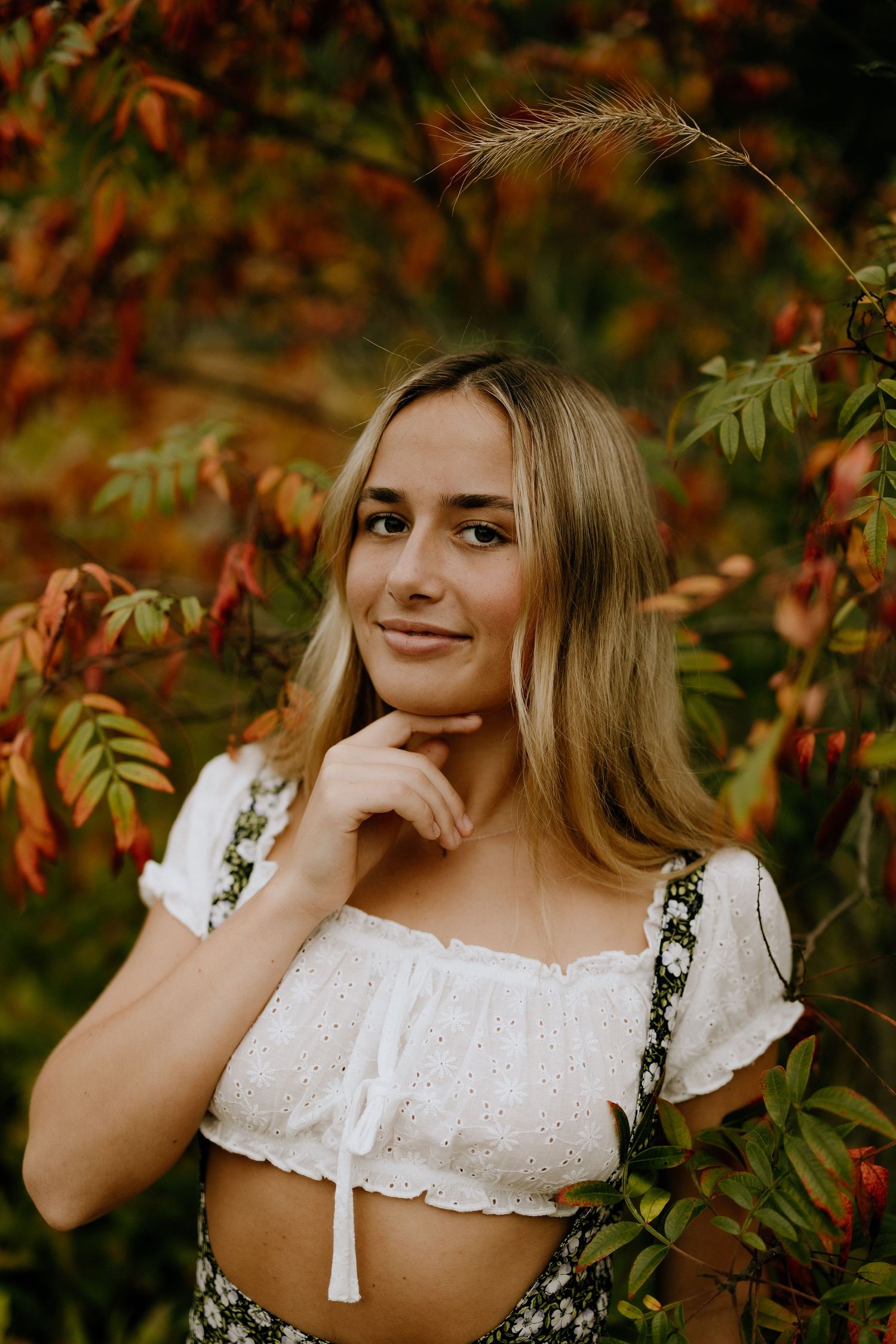 A fashionable crop top outfit against autumn foliage in warm lighting creates a dreamy outdoor portrait.