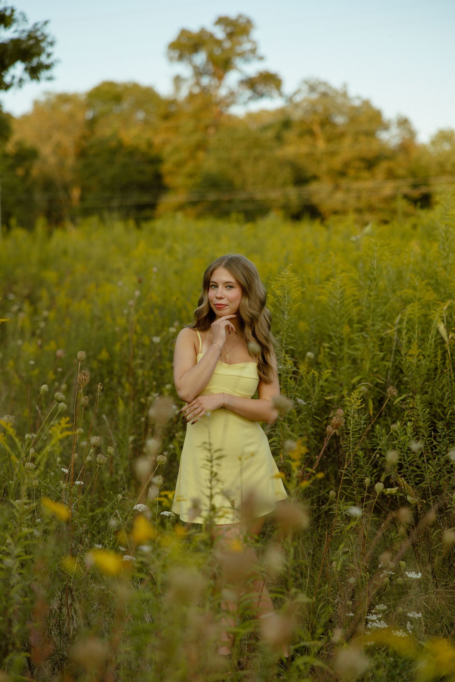 Artistic outdoor photoshoot in a wildflower meadow during golden hour with yellow summer dress.