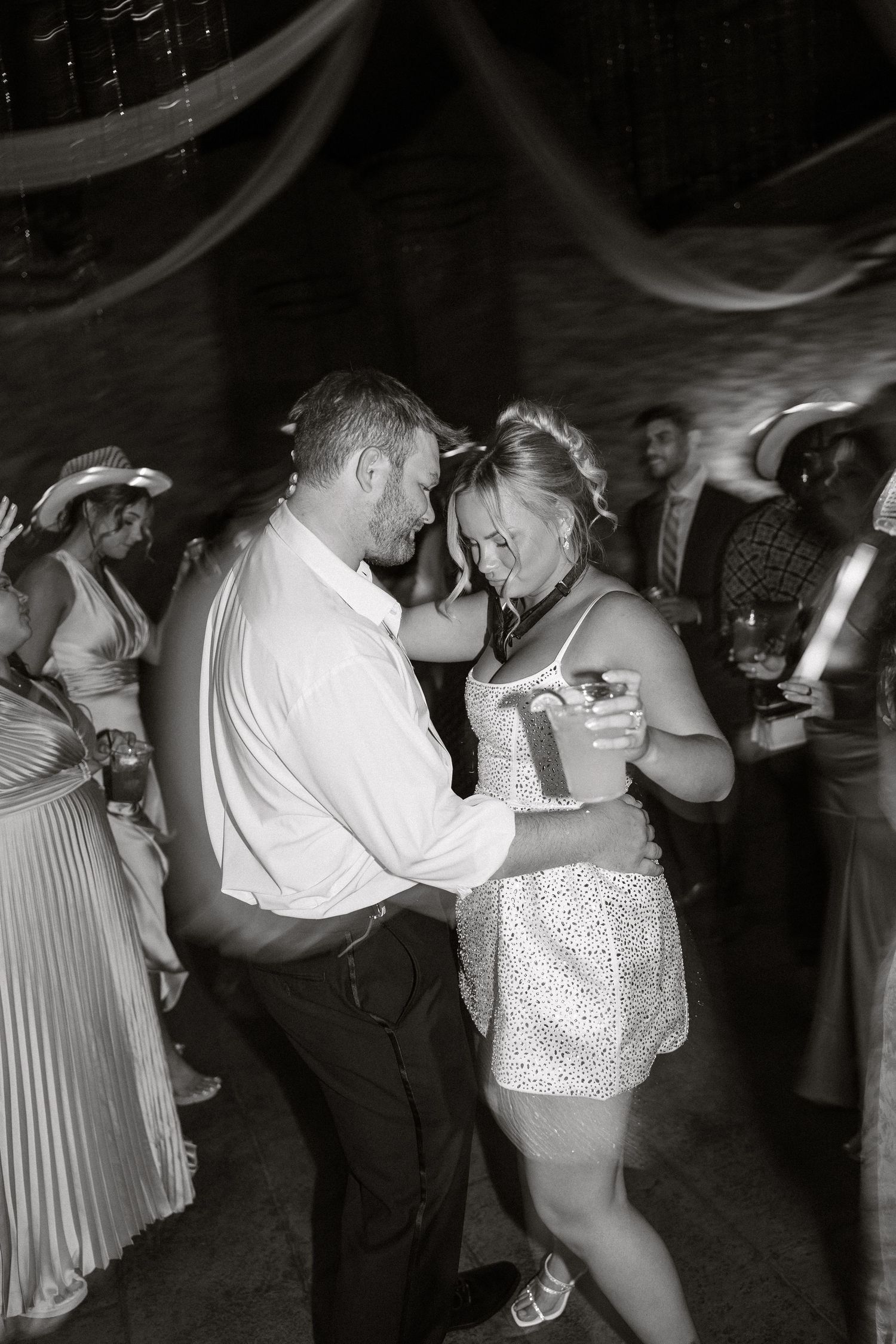 A black and white photo of a couple dancing intimately at a wedding reception.