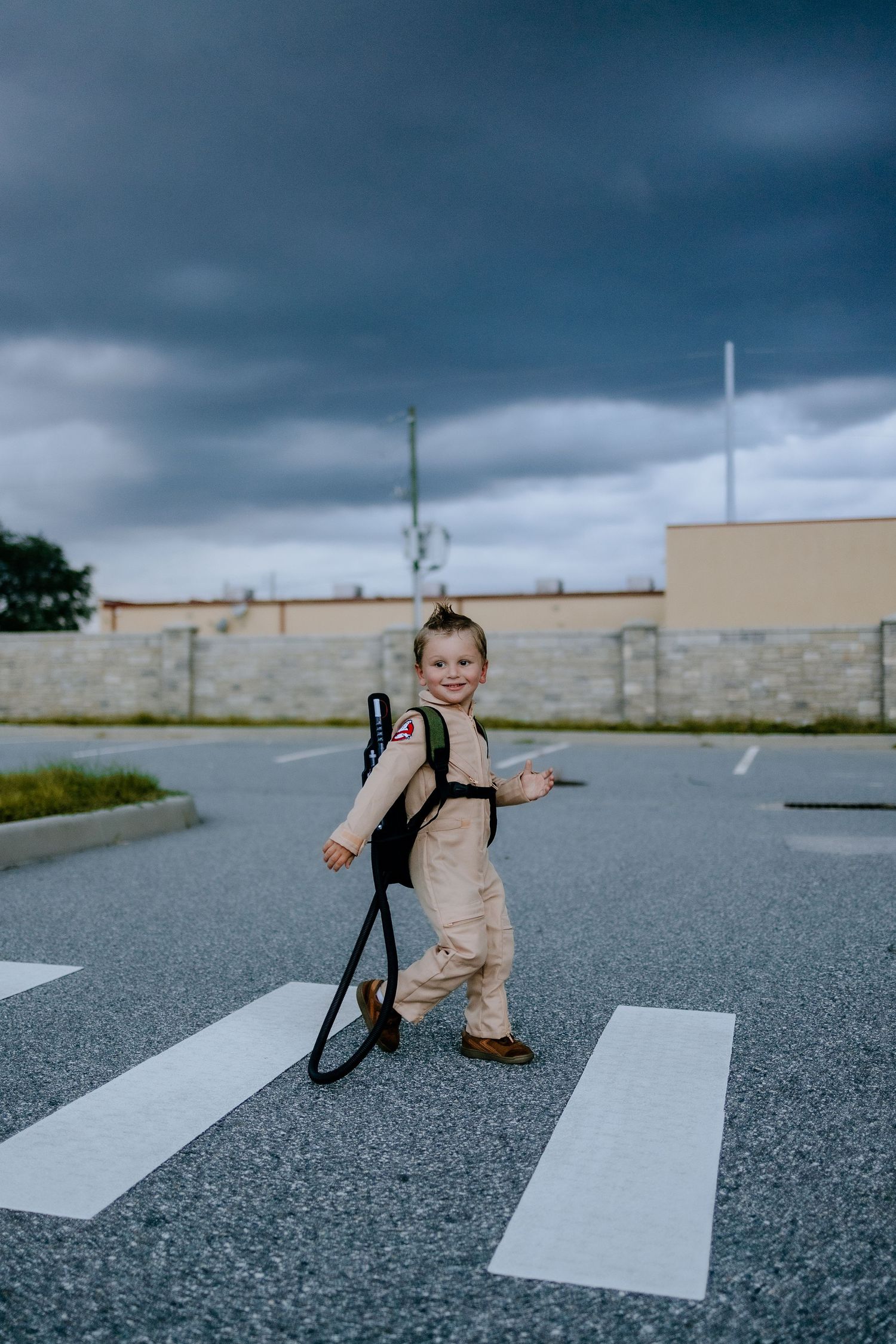 A playful ghostbuster costume brightens a cloudy day in an empty parking lot.