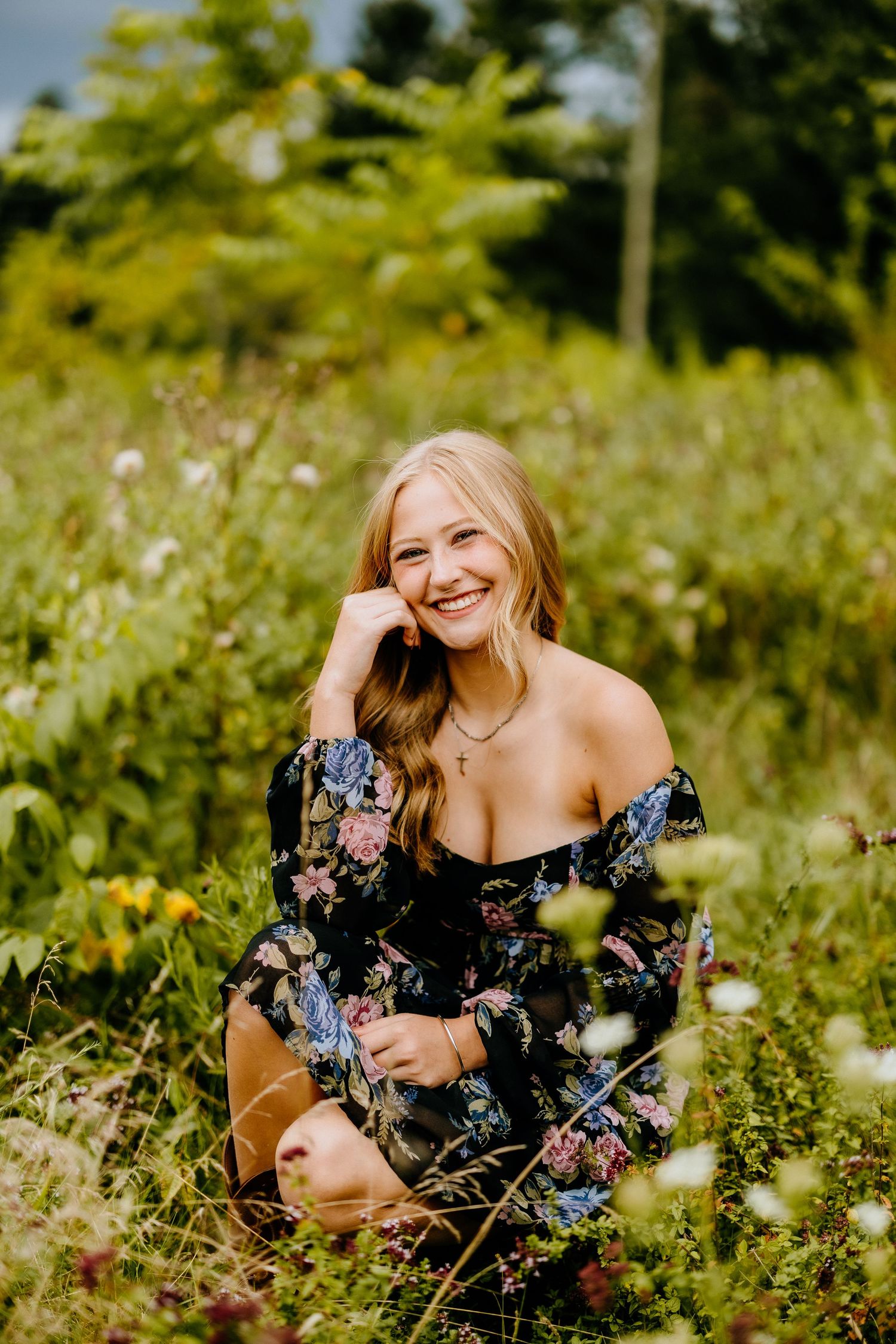 Person wearing floral dress poses in wildflower meadow with natural lighting.