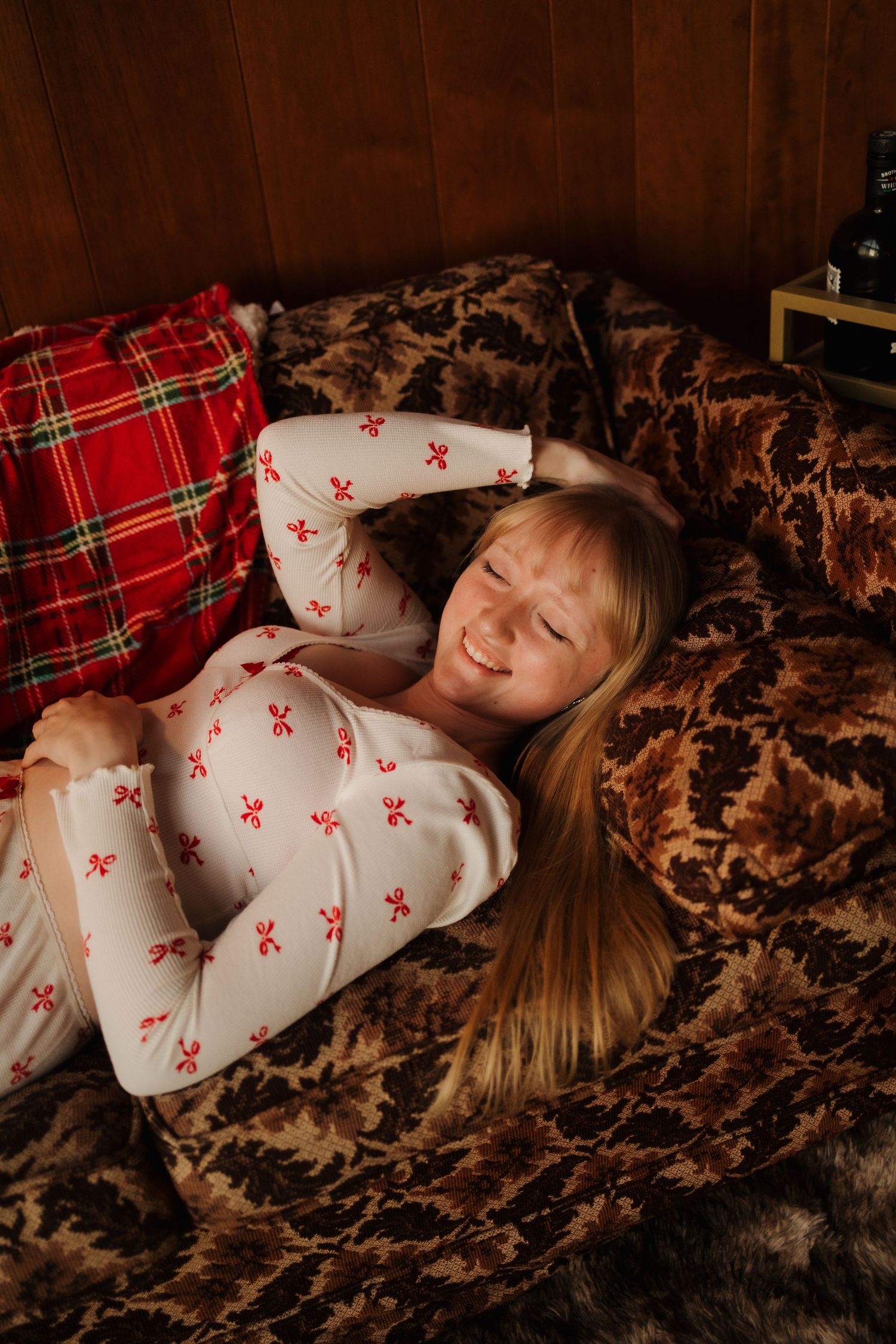 Person lying on brown couch wearing festive red and white pajamas.