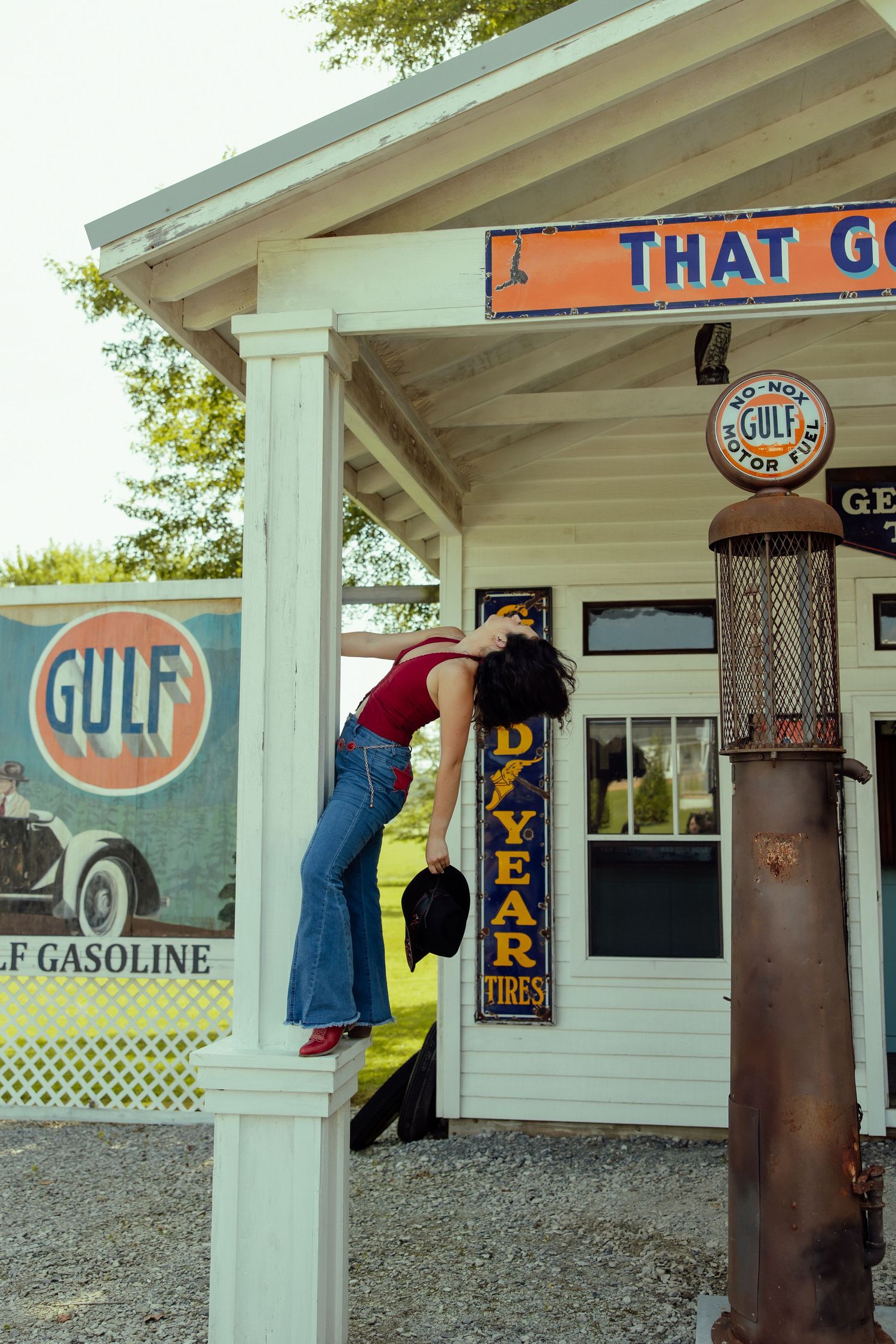 Person climbing on wall of vintage Gulf gas station with retro signage.