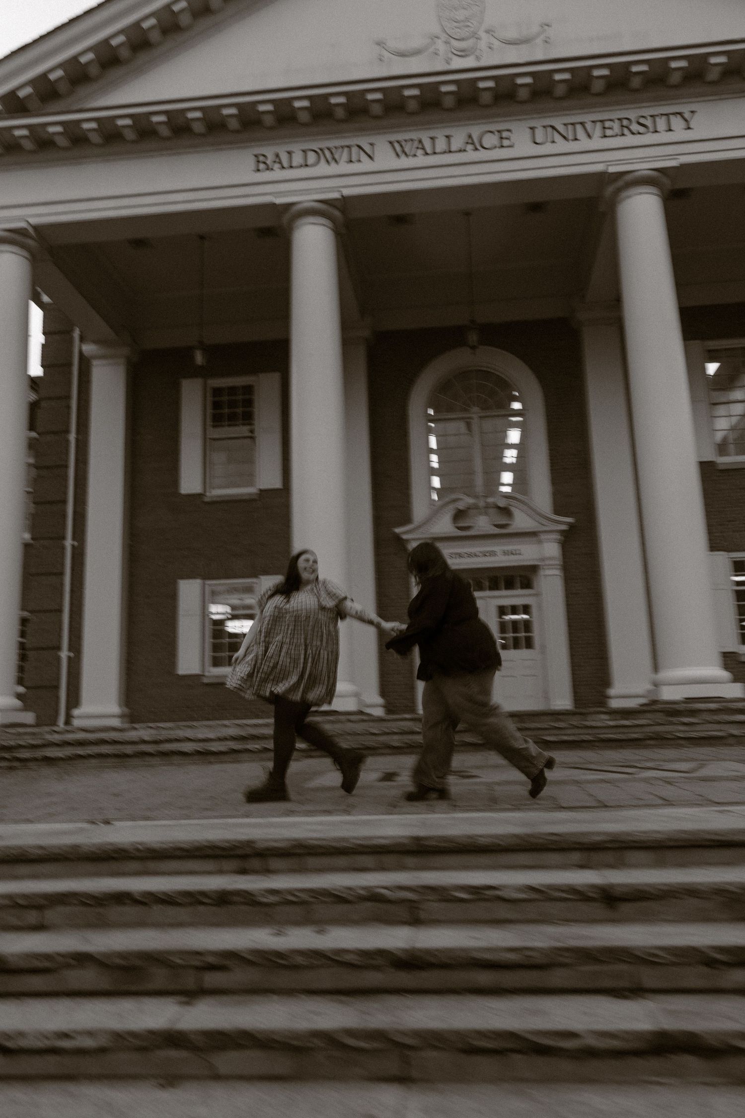 Students walk past the grand columned entrance of Baldwin Wallace University's historic building on a cloudy day.