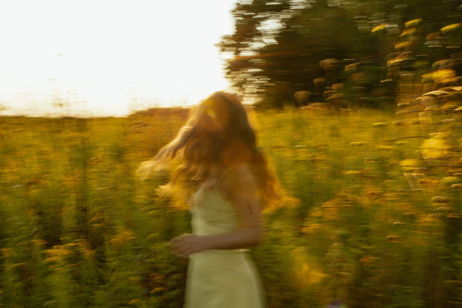 A person running through a golden sunlit field at sunset creating a dreamy motion blur effect.